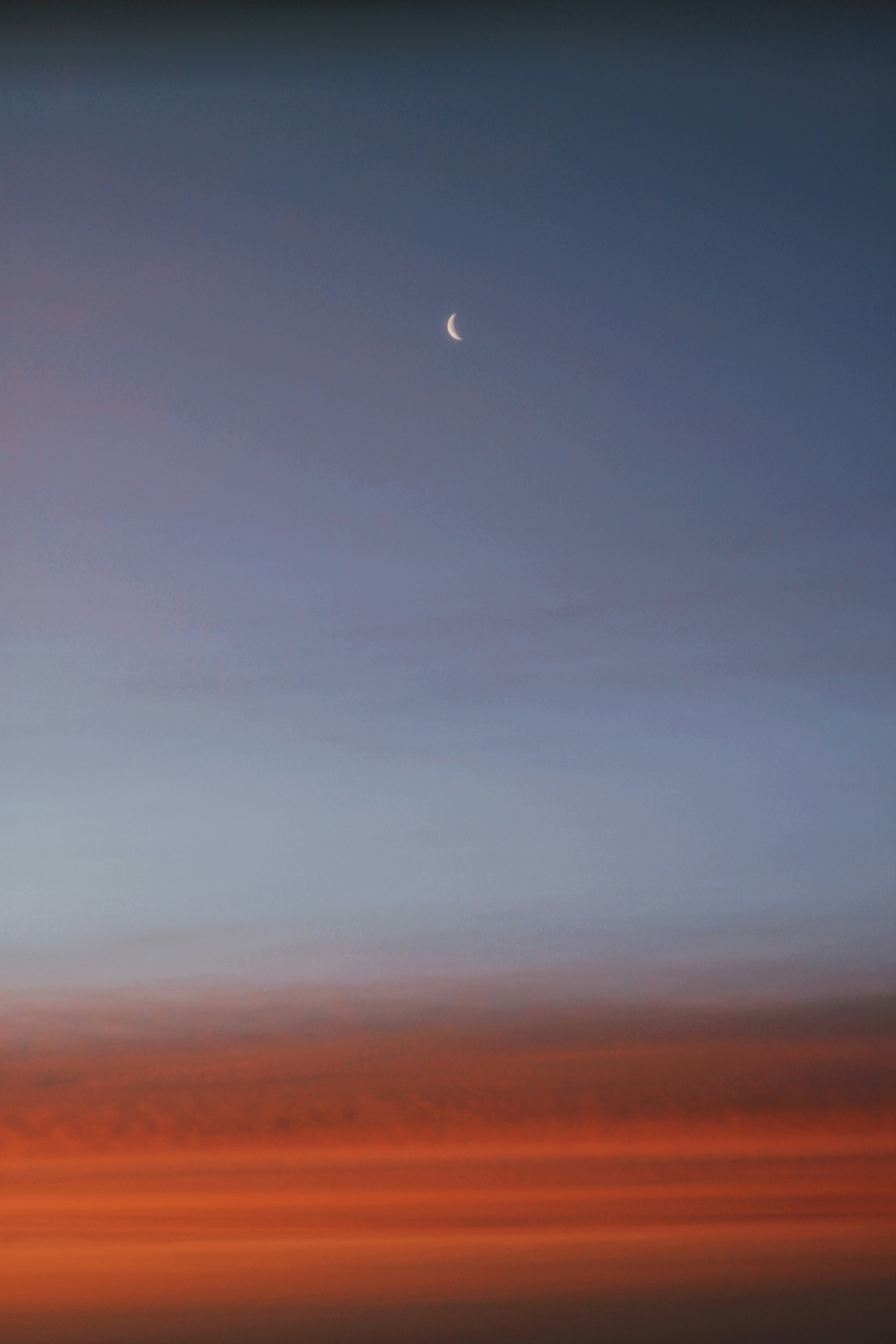Lua crescente em um céu crepuscular com nuvens laranja