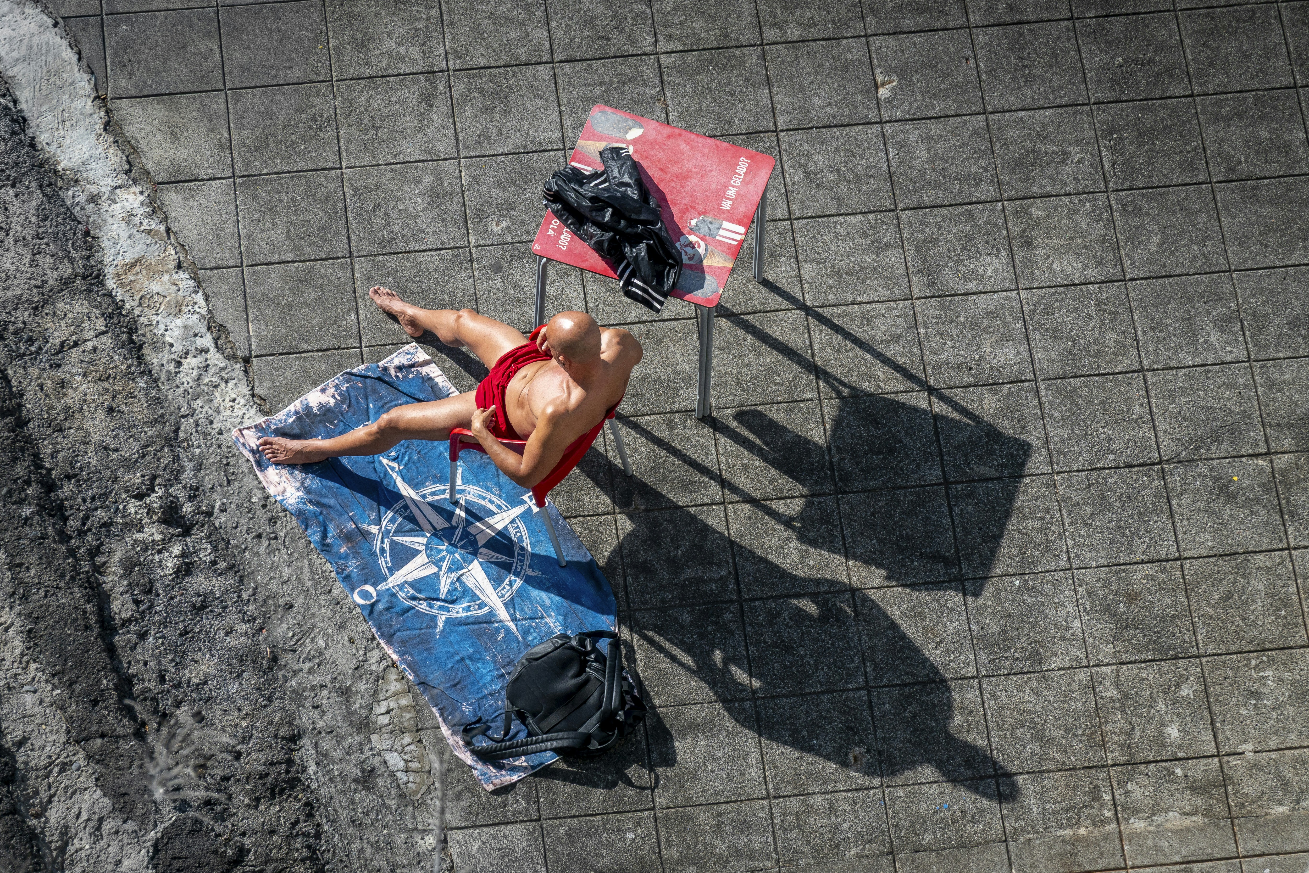 Man in red swimsuit sunbathing on towel.