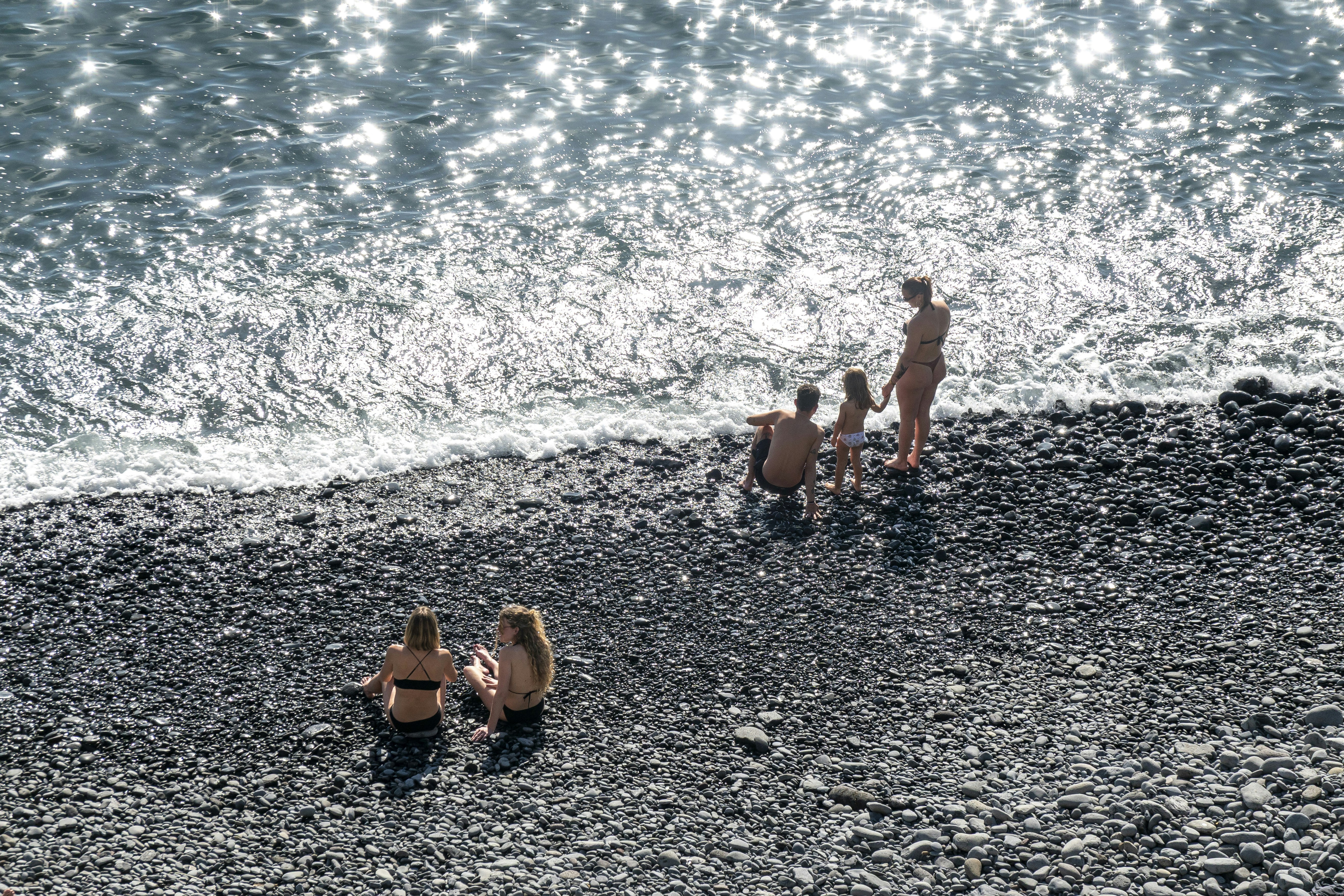 People relaxing on a pebble beach by the ocean
