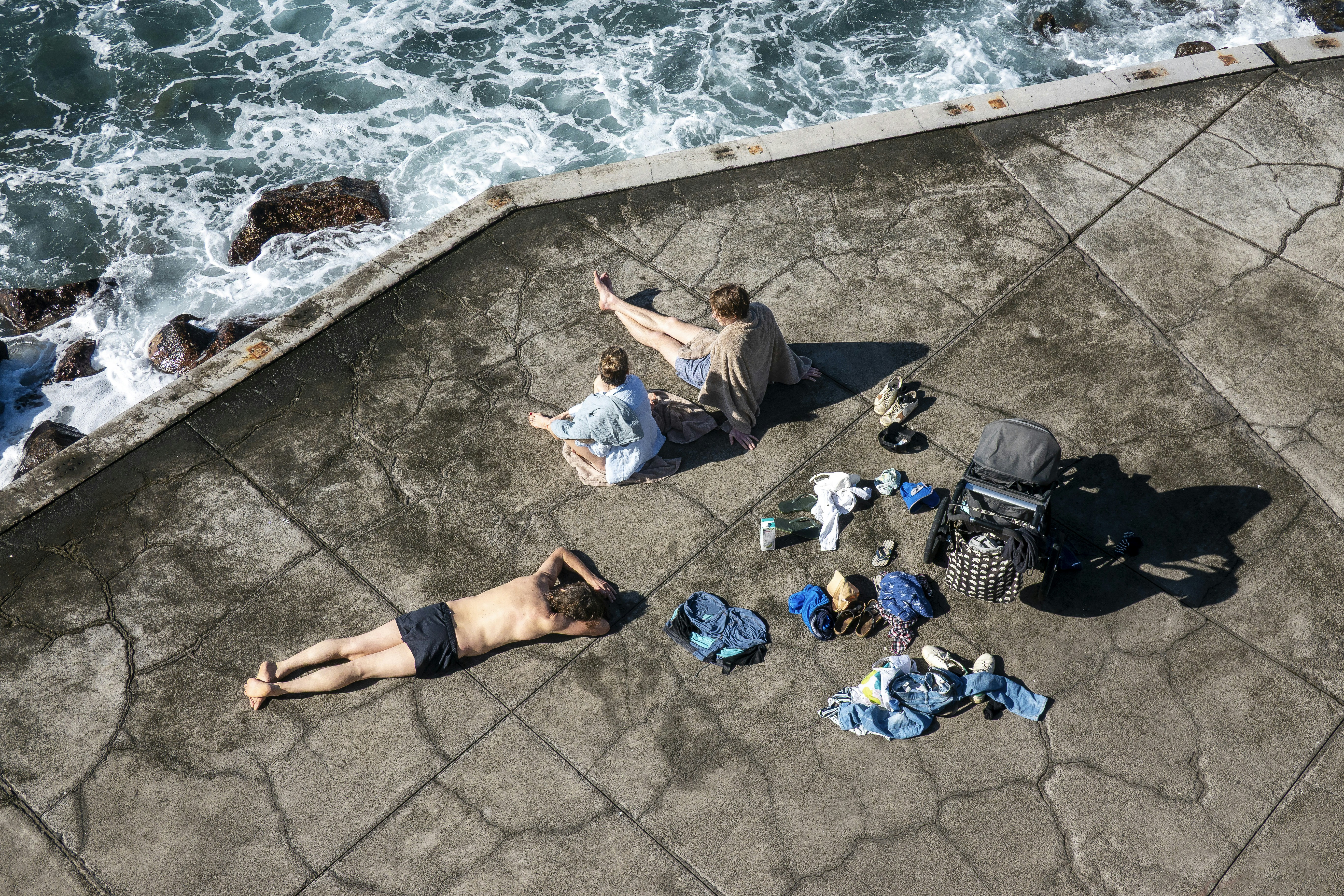 People relaxing on a concrete surface by the ocean.