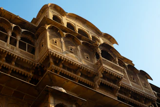 Ornate sandstone building with intricate carvings under blue sky