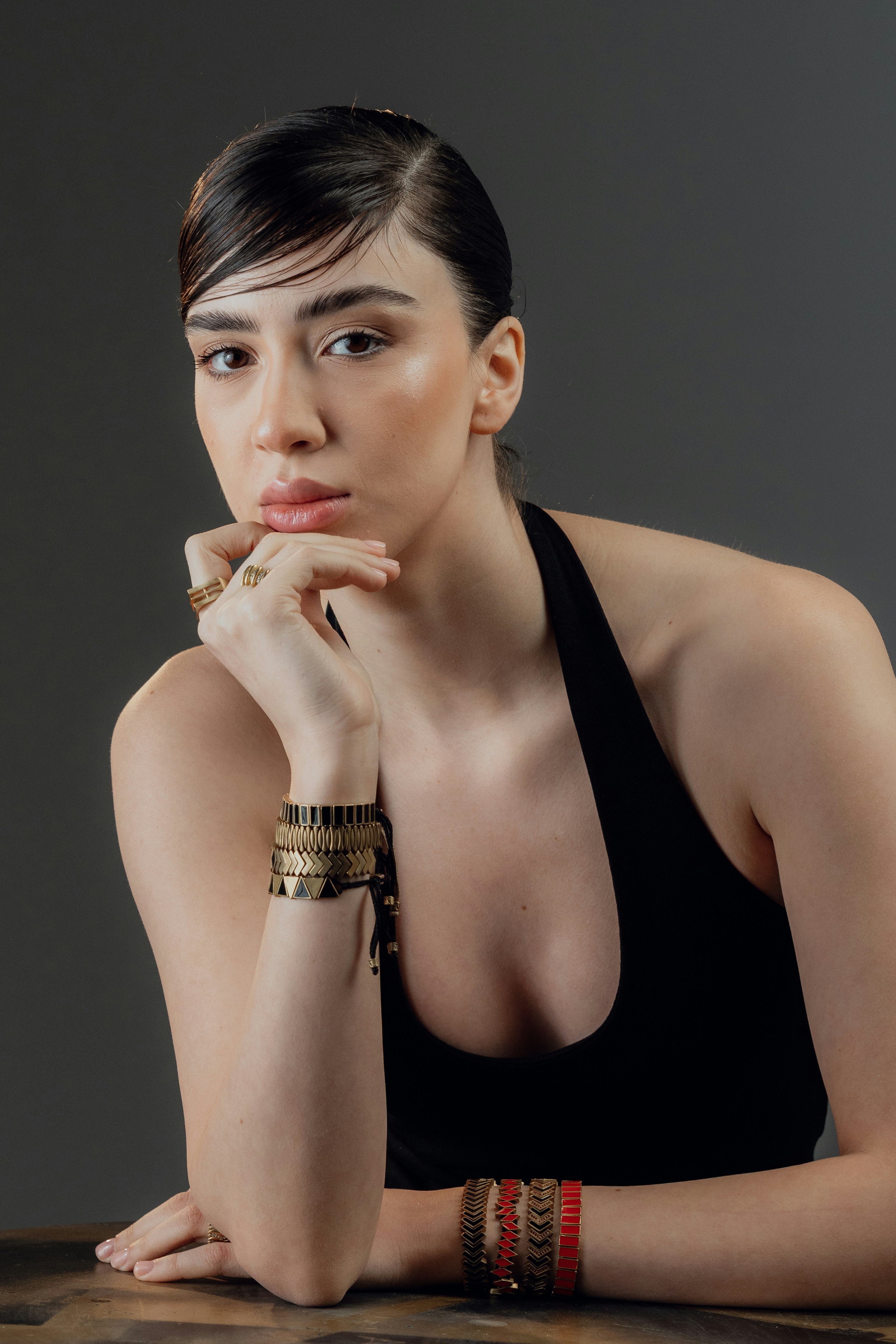 Young woman with jewelry rests chin on hand