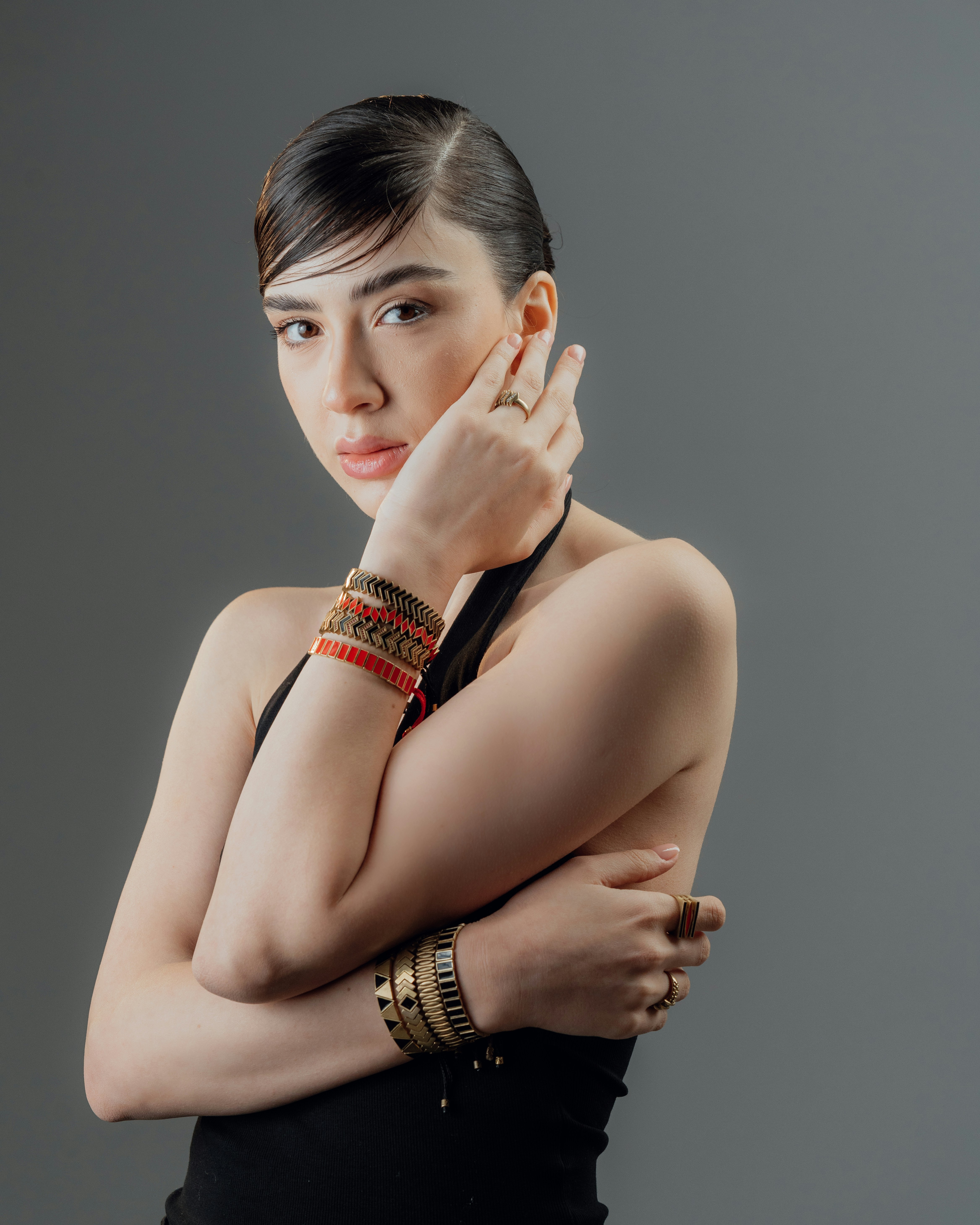 Young woman with bracelets on gray background