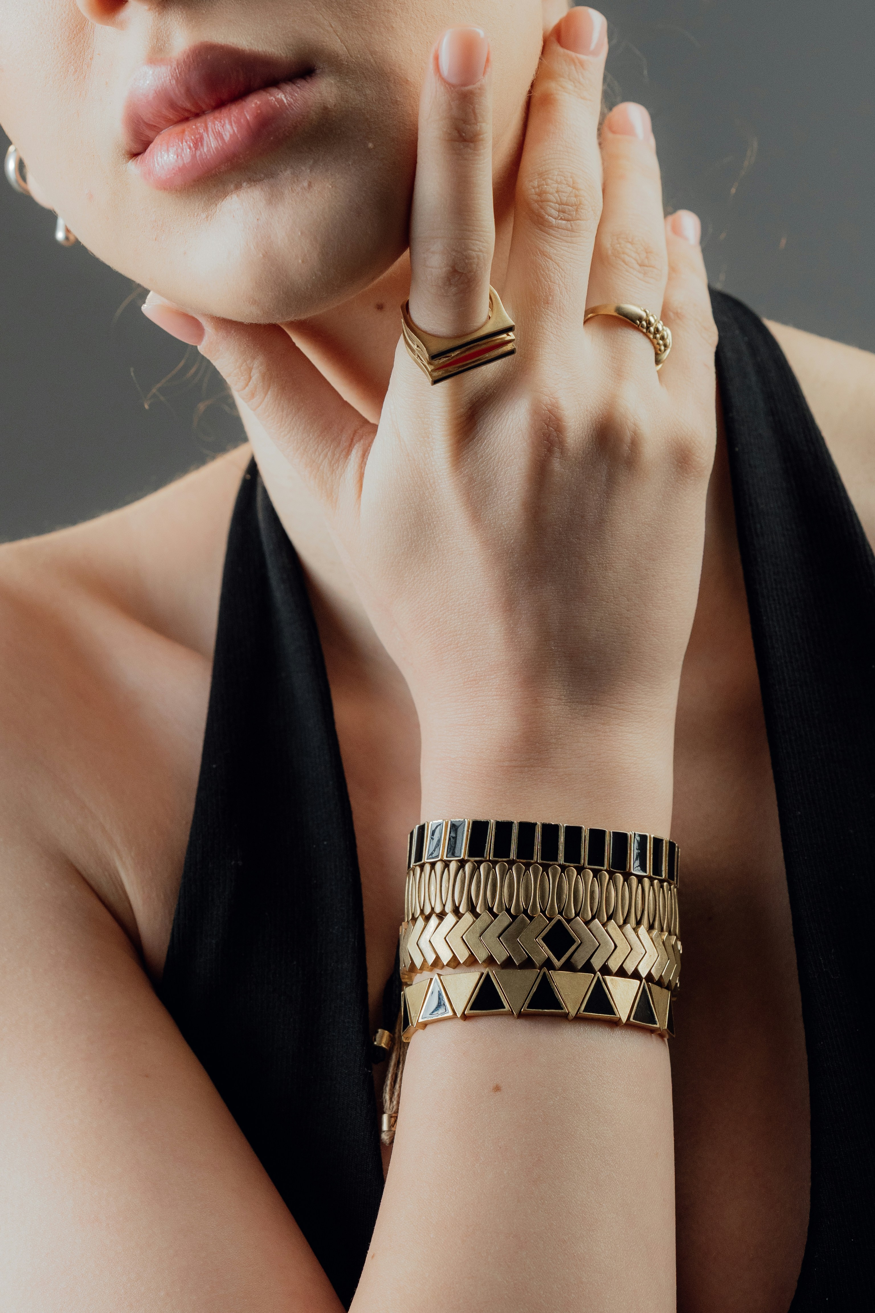 Mulher usando pulseiras e anéis de ouro empilhados