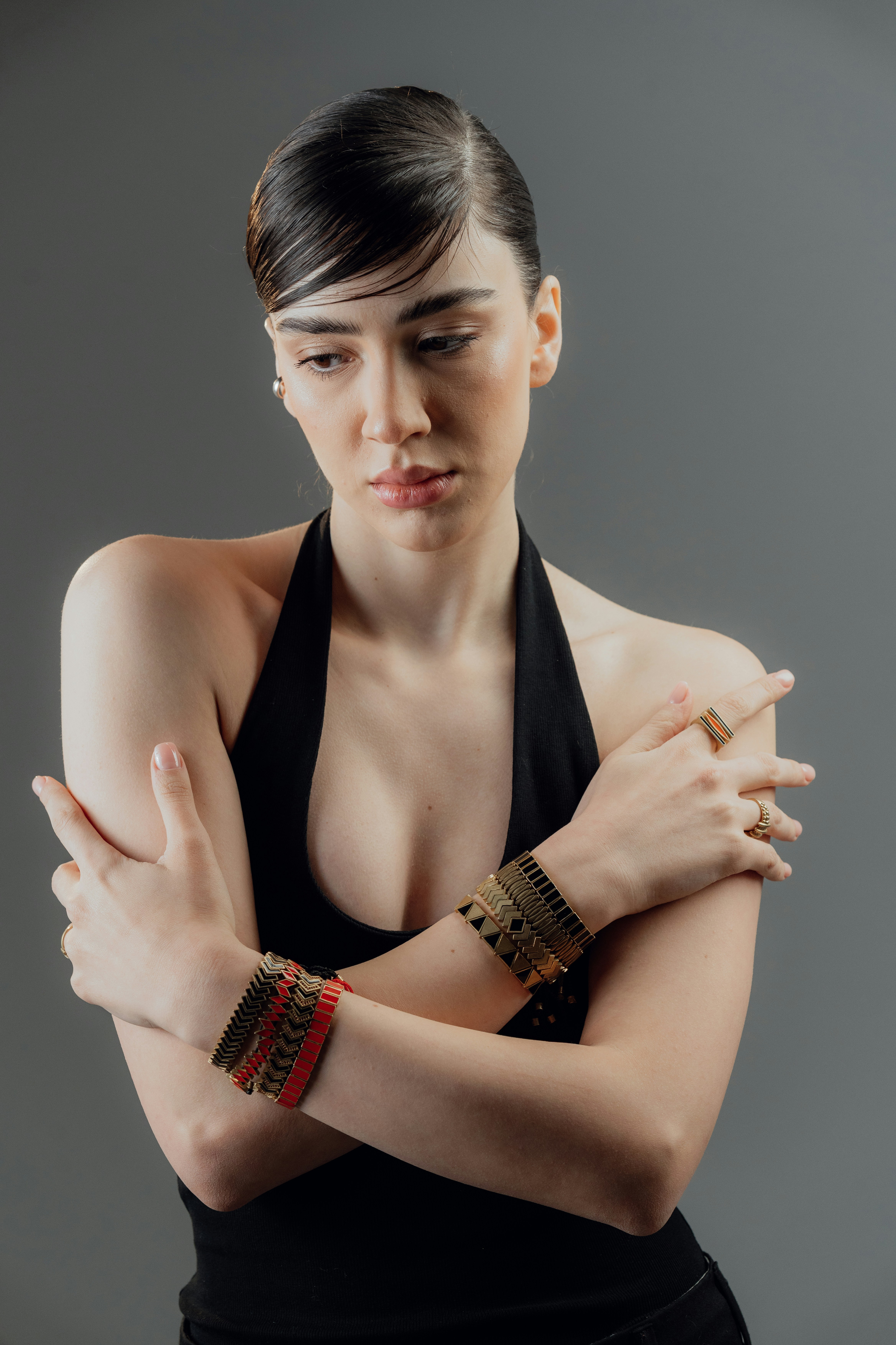 Mulher de braços cruzados usando pulseiras e anéis