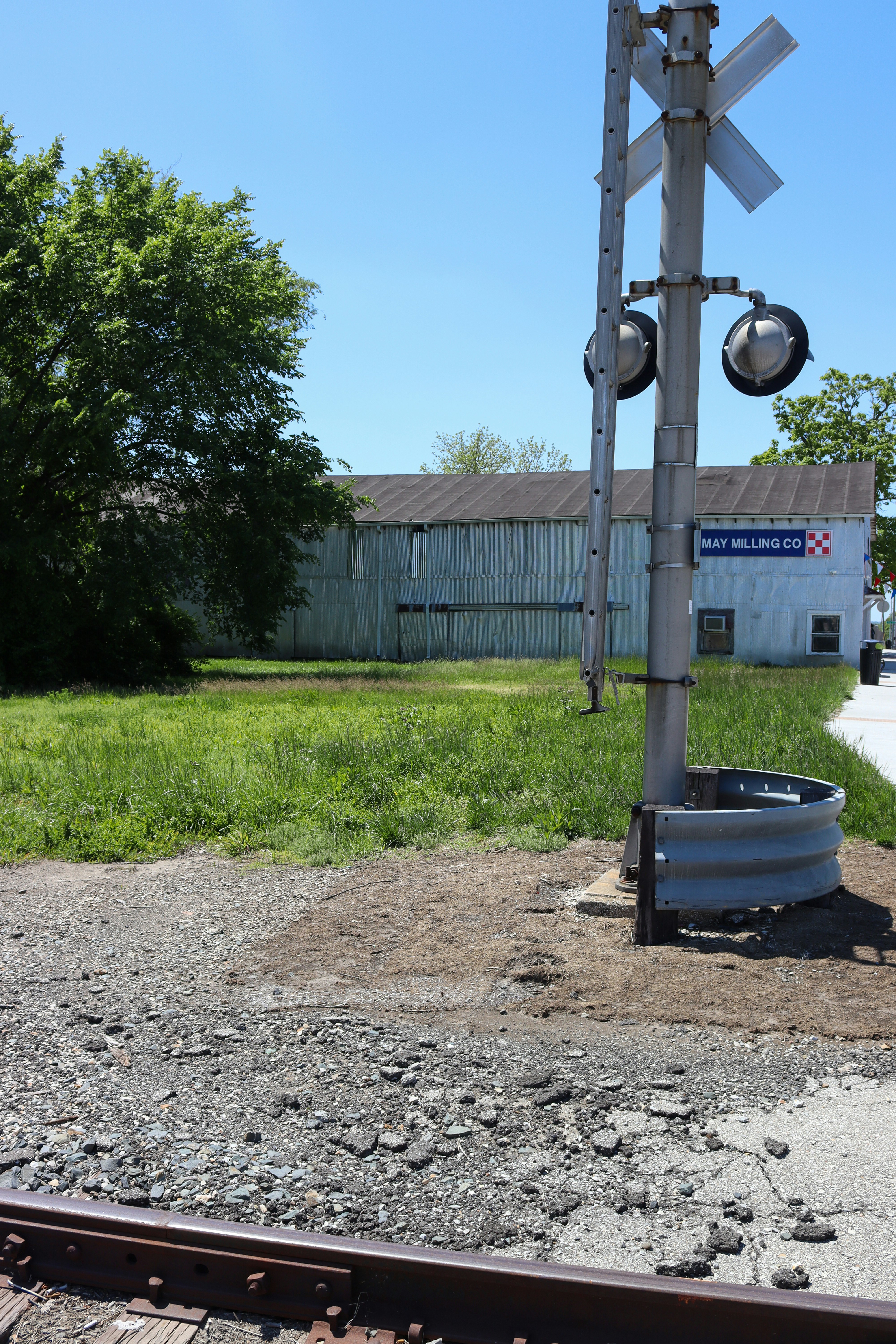 Railroad crossing signal with a building in background.