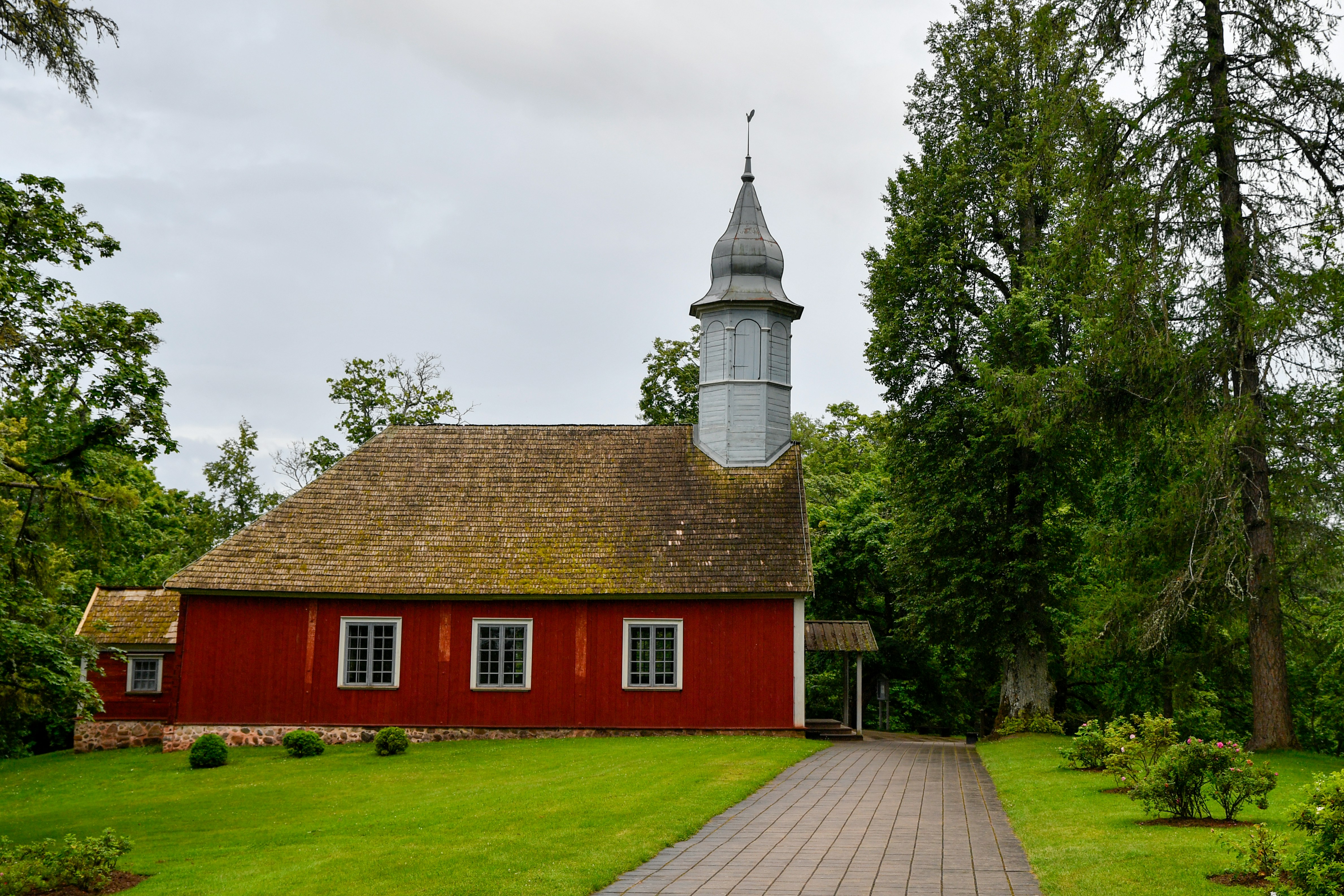A red wooden church with a tall steeple.