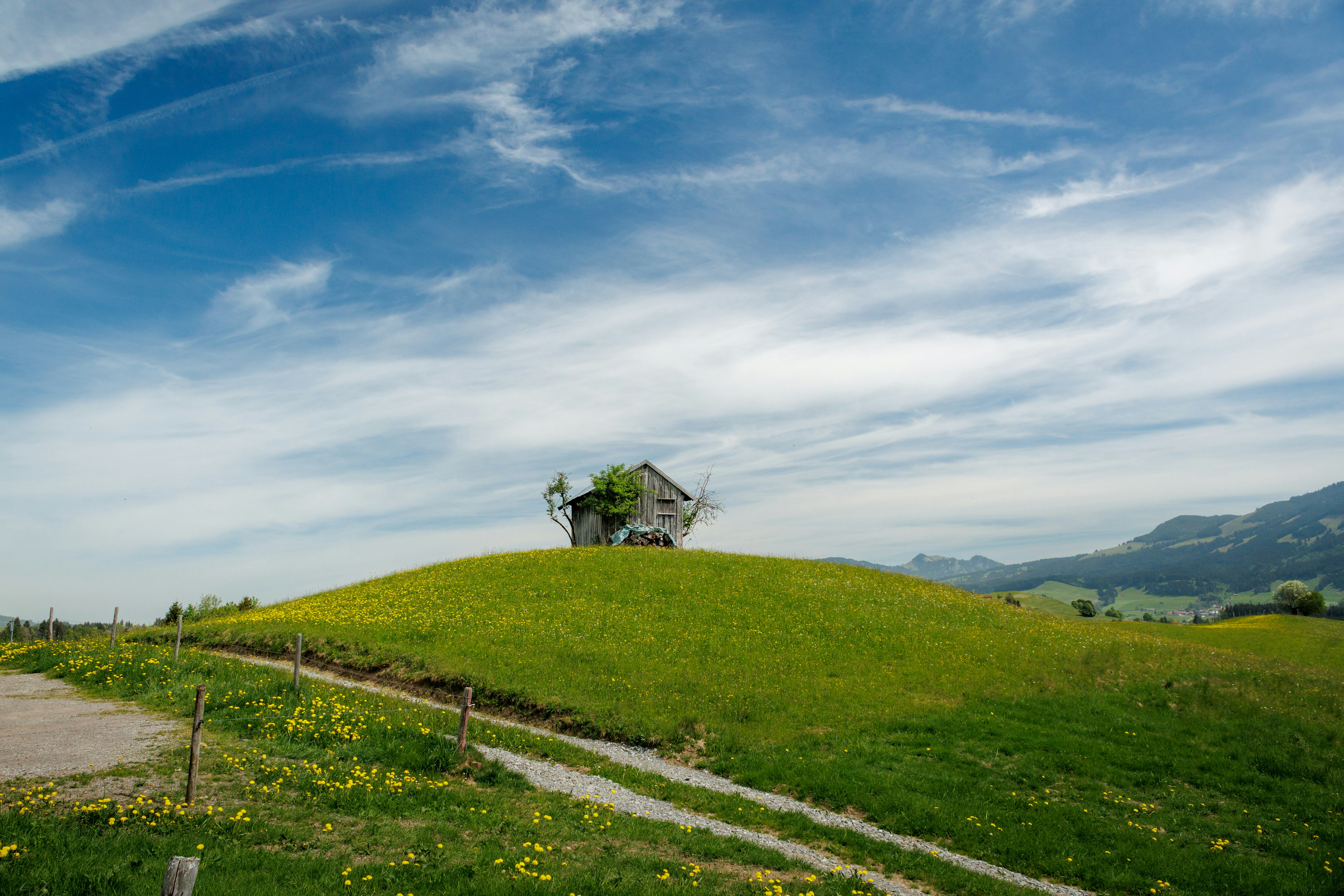 Una pequeña casa desgastada se alza en la cima de una colina verde cubierta de hierba.