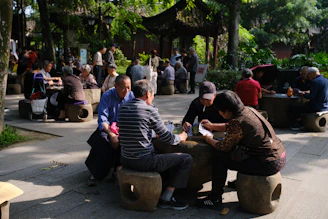 People playing games at stone tables in a park.