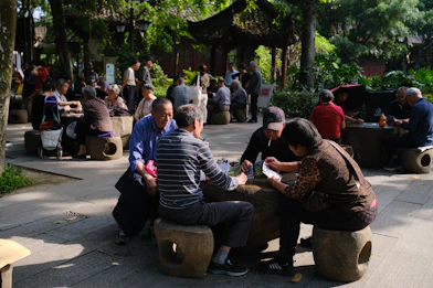 People playing games at stone tables in a park.