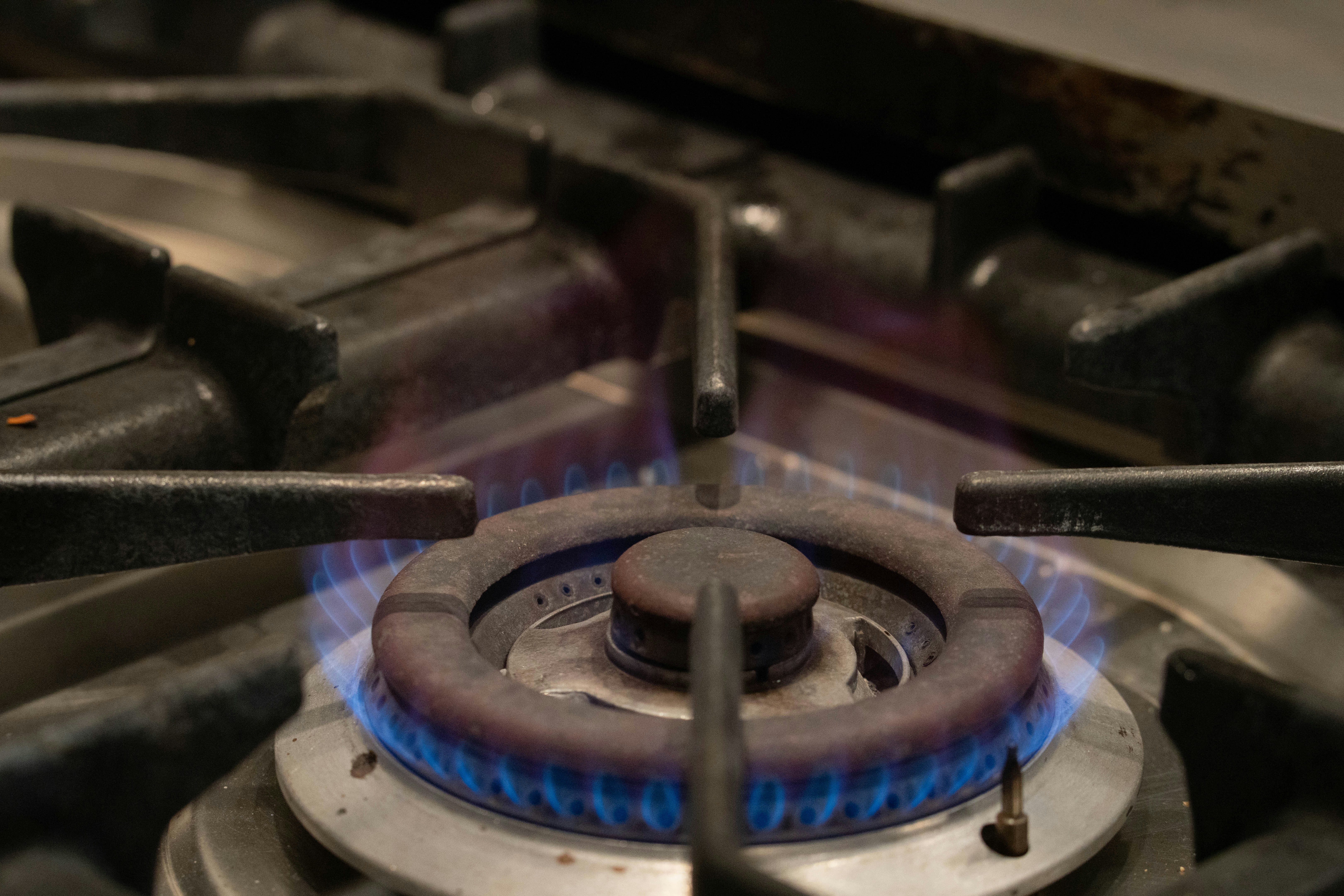 Un primo piano di un fornello a gas con fiamme blu.