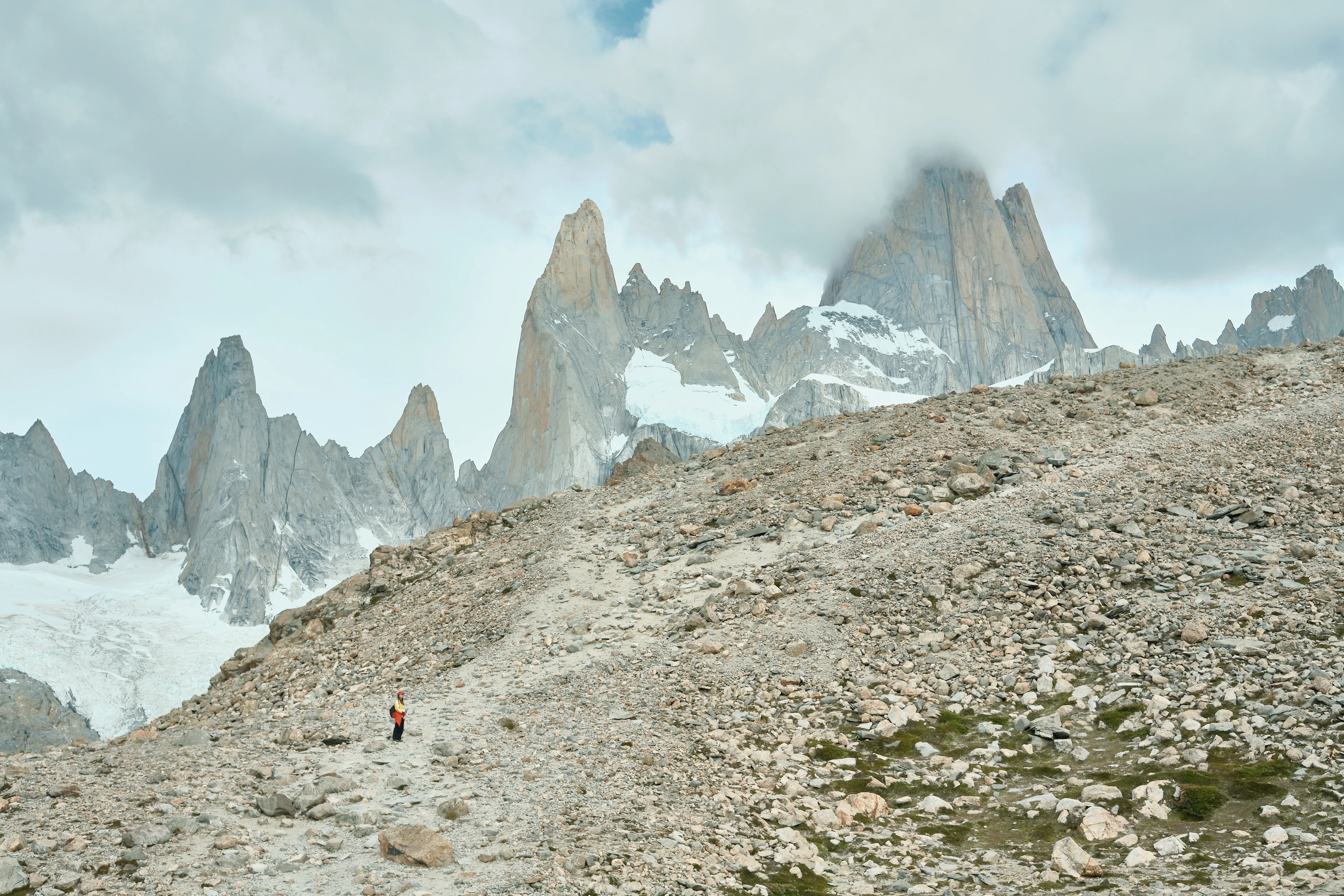 A hiker climbing towards Laguna de los Tres beneath the granite spires of the Fitz Roy massif