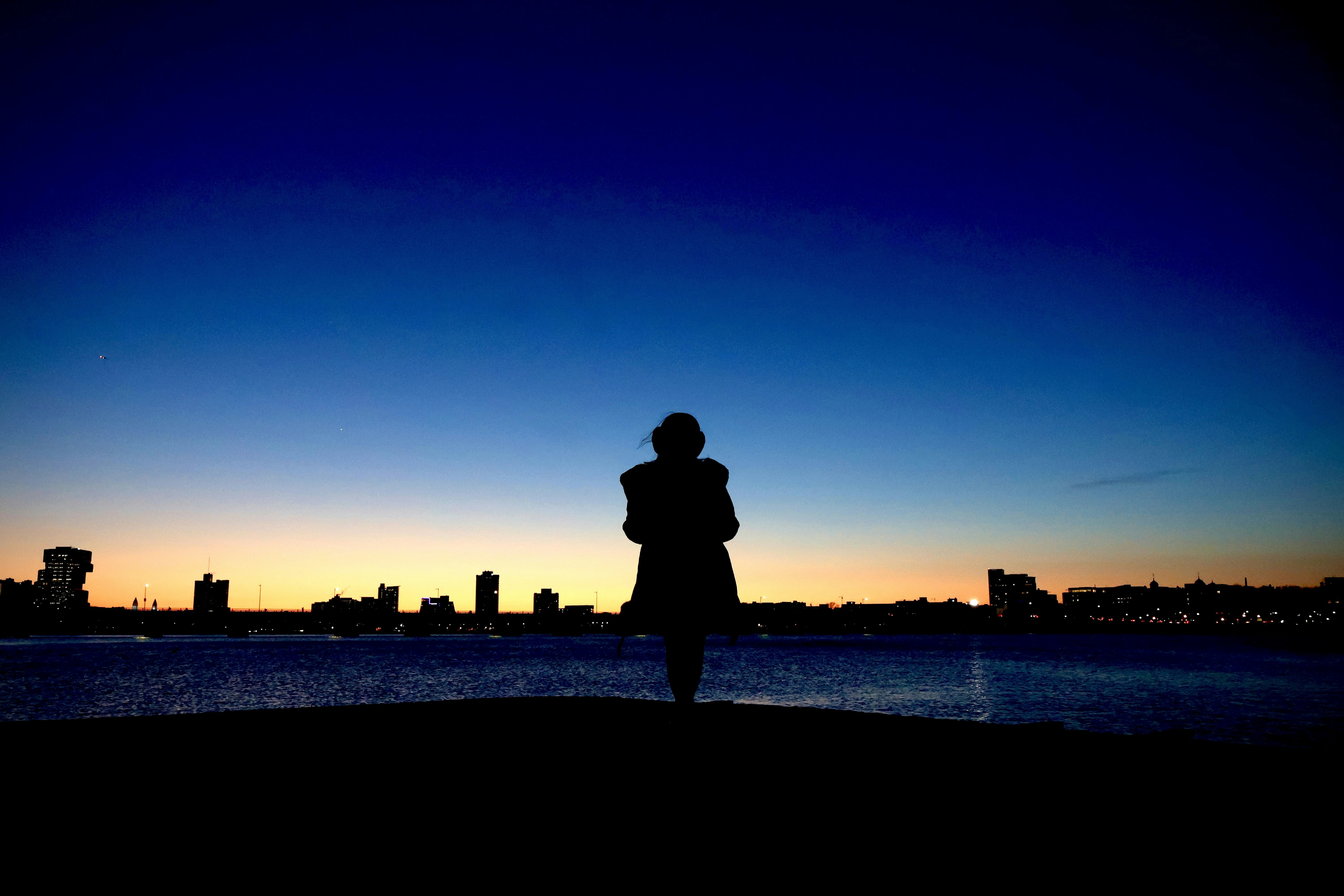 Silueta de una persona contra el horizonte de la ciudad al anochecer
