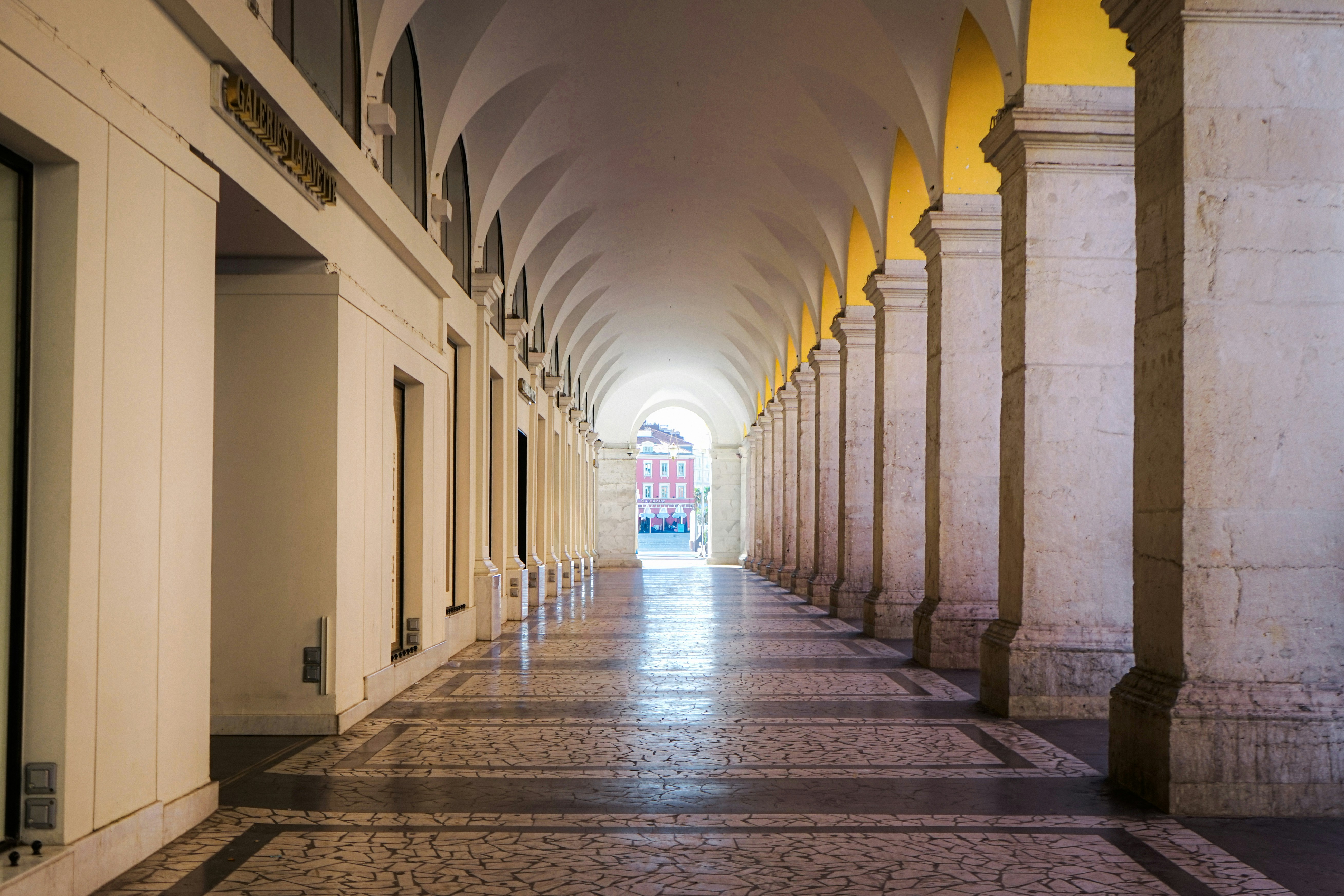 A long arched colonnade with marble columns and tiled floor.