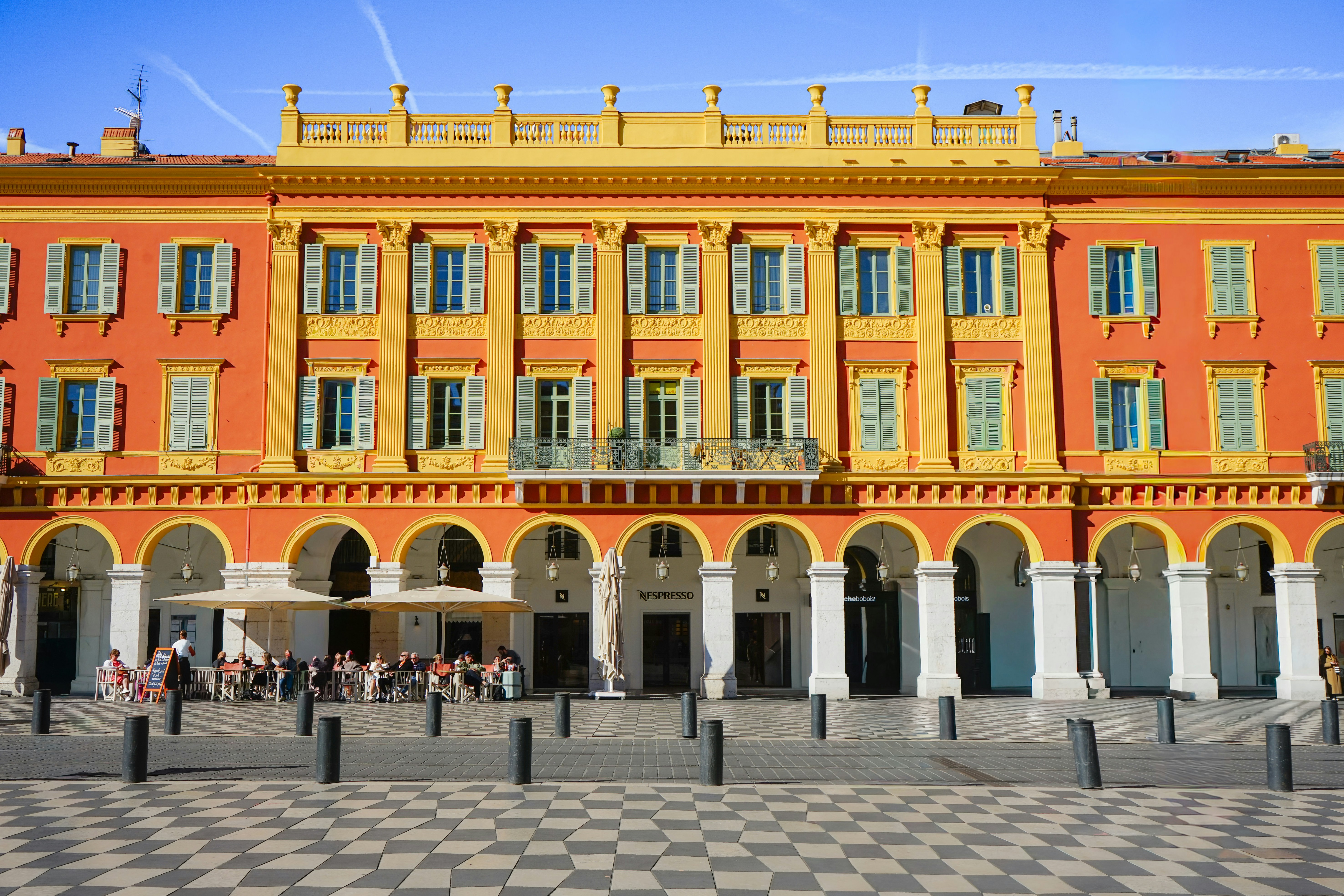 Orange building with arched colonnade and checkerboard plaza