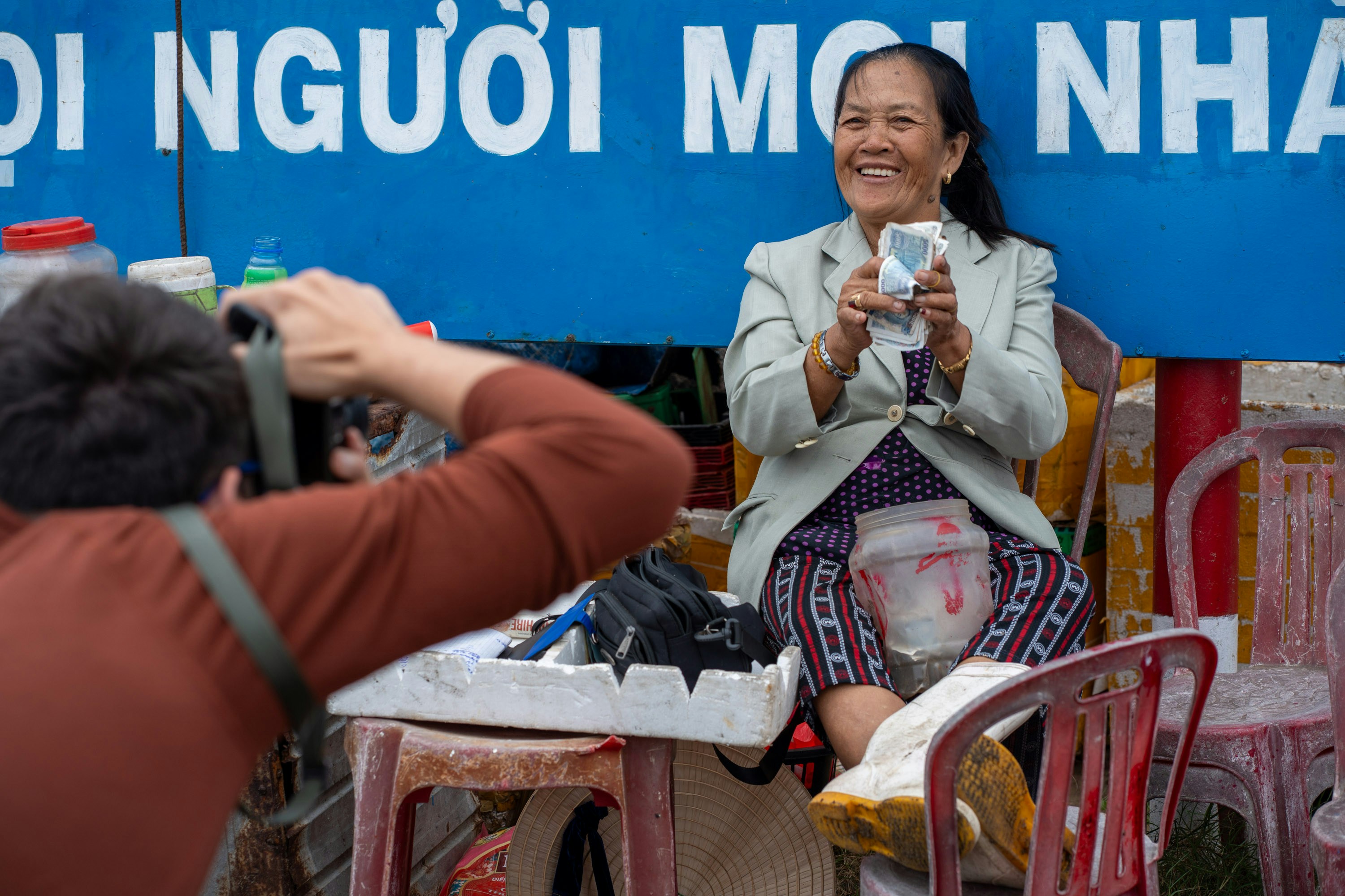 Woman smiles while holding a phone, being photographed