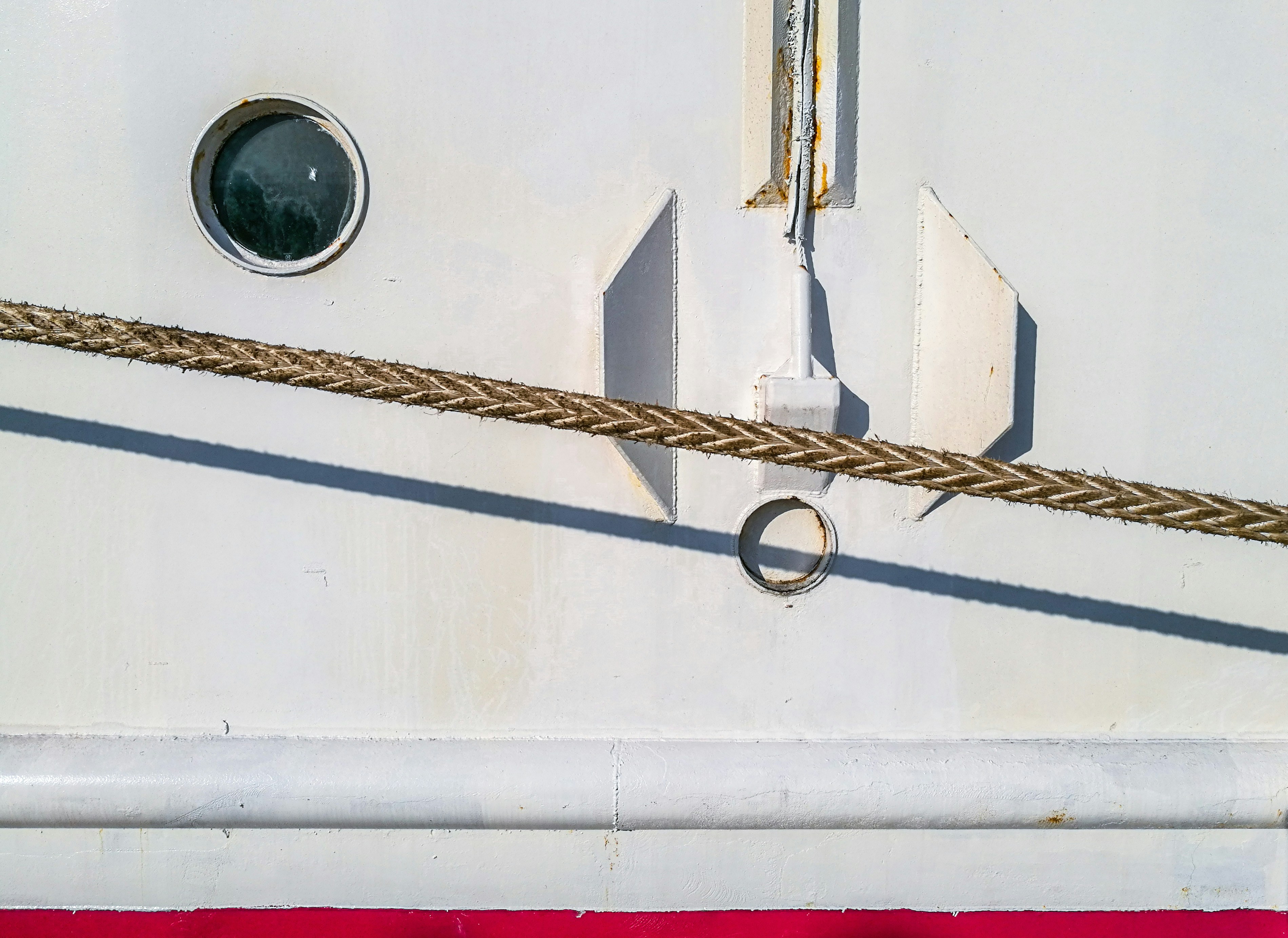 Close do casco branco de um navio com uma escotilha.