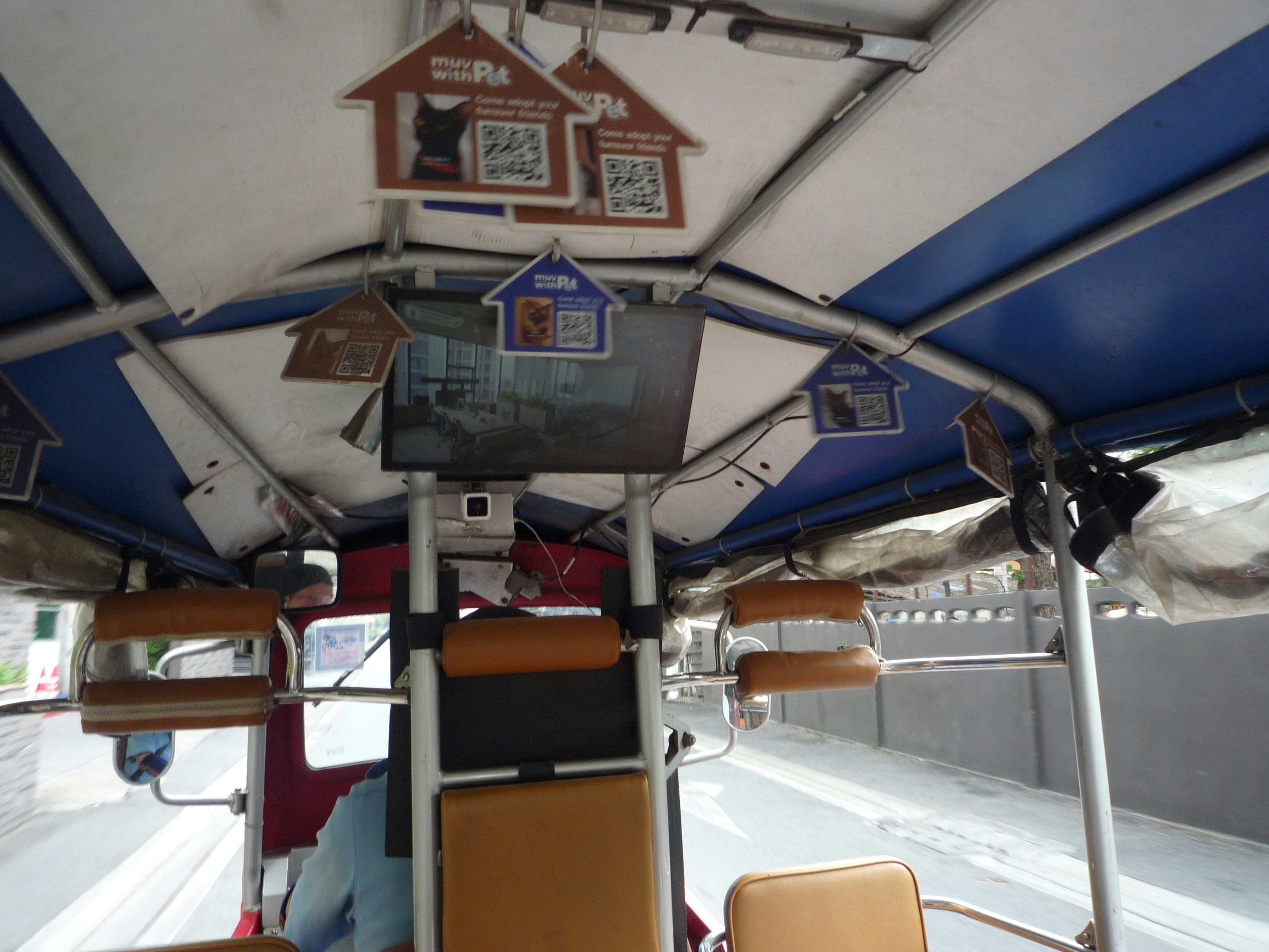 Interior of a tuk-tuk with decorative signs and screens