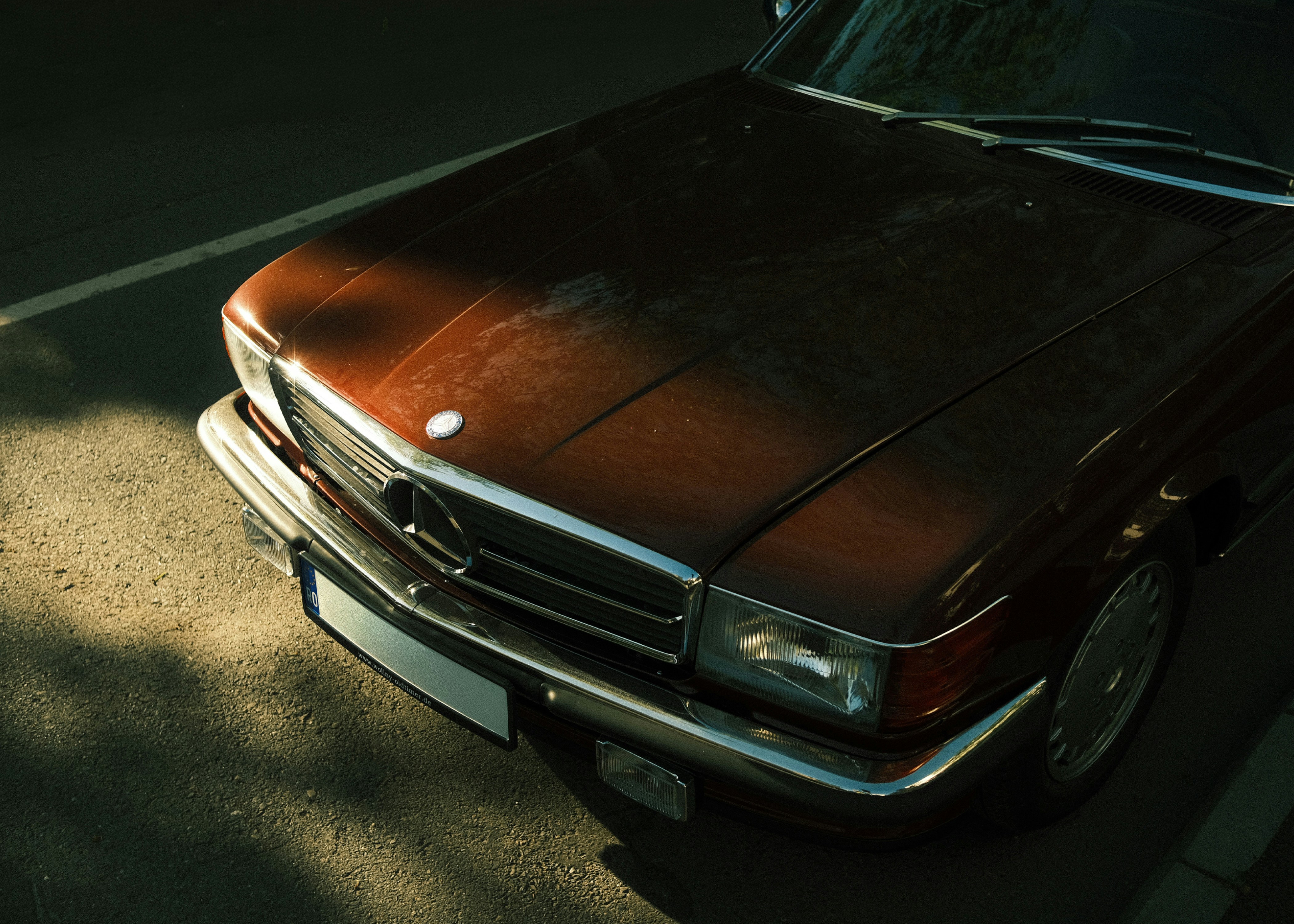 Vintage brown mercedes hood with sunlight patterns.