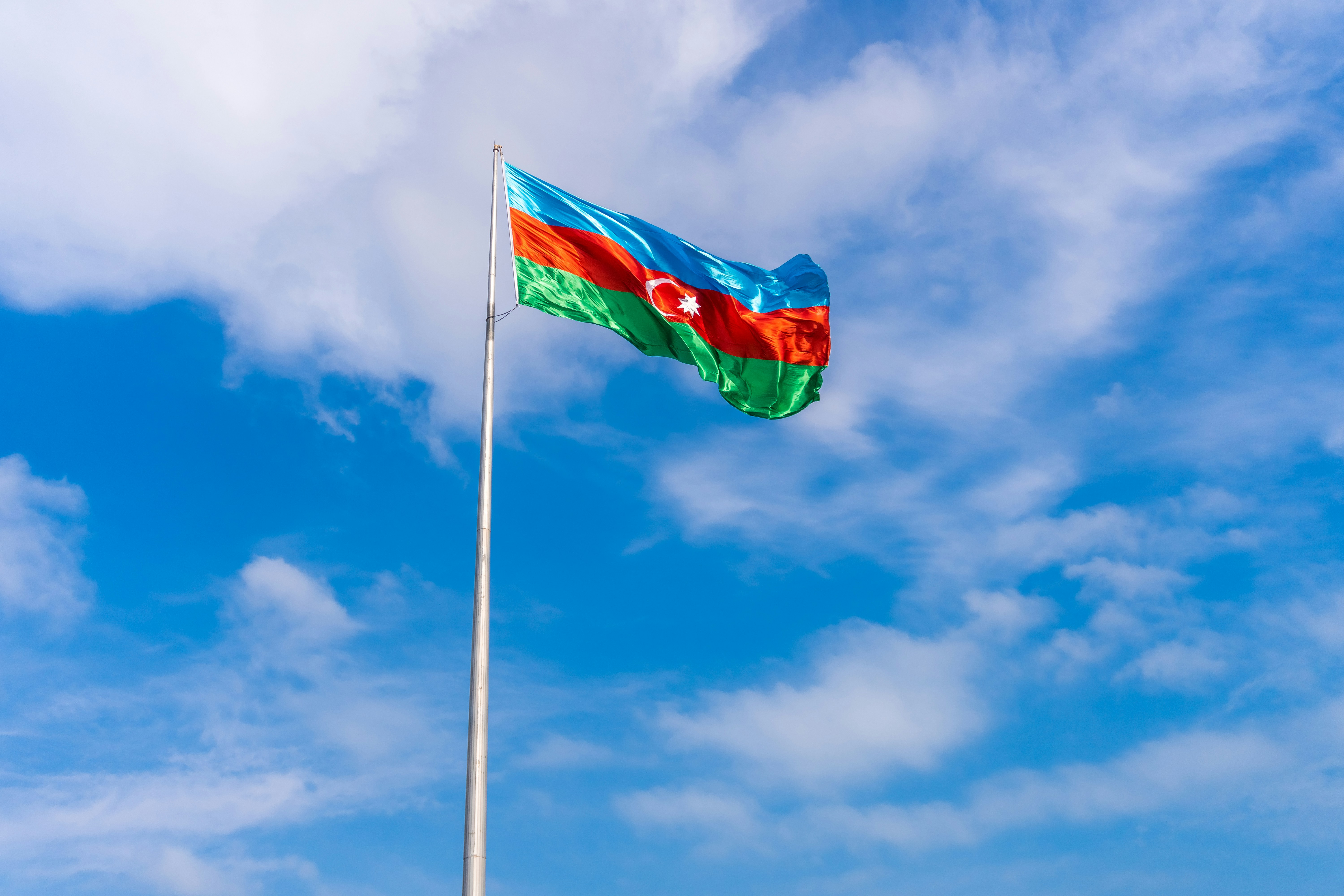The azerbaijani flag waves against a blue sky.