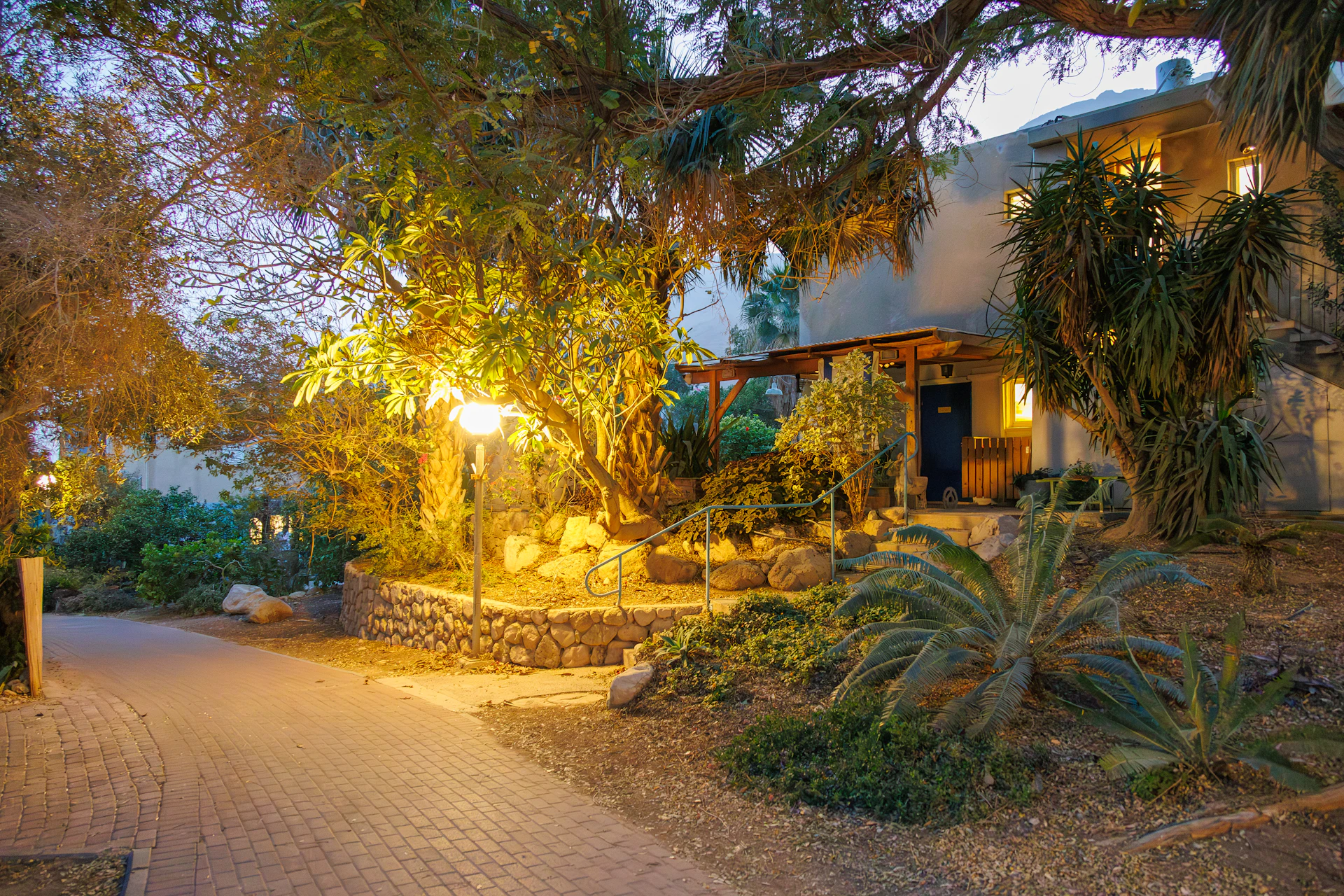 Caminho de jardim iluminado por balizadores ao entardecer
