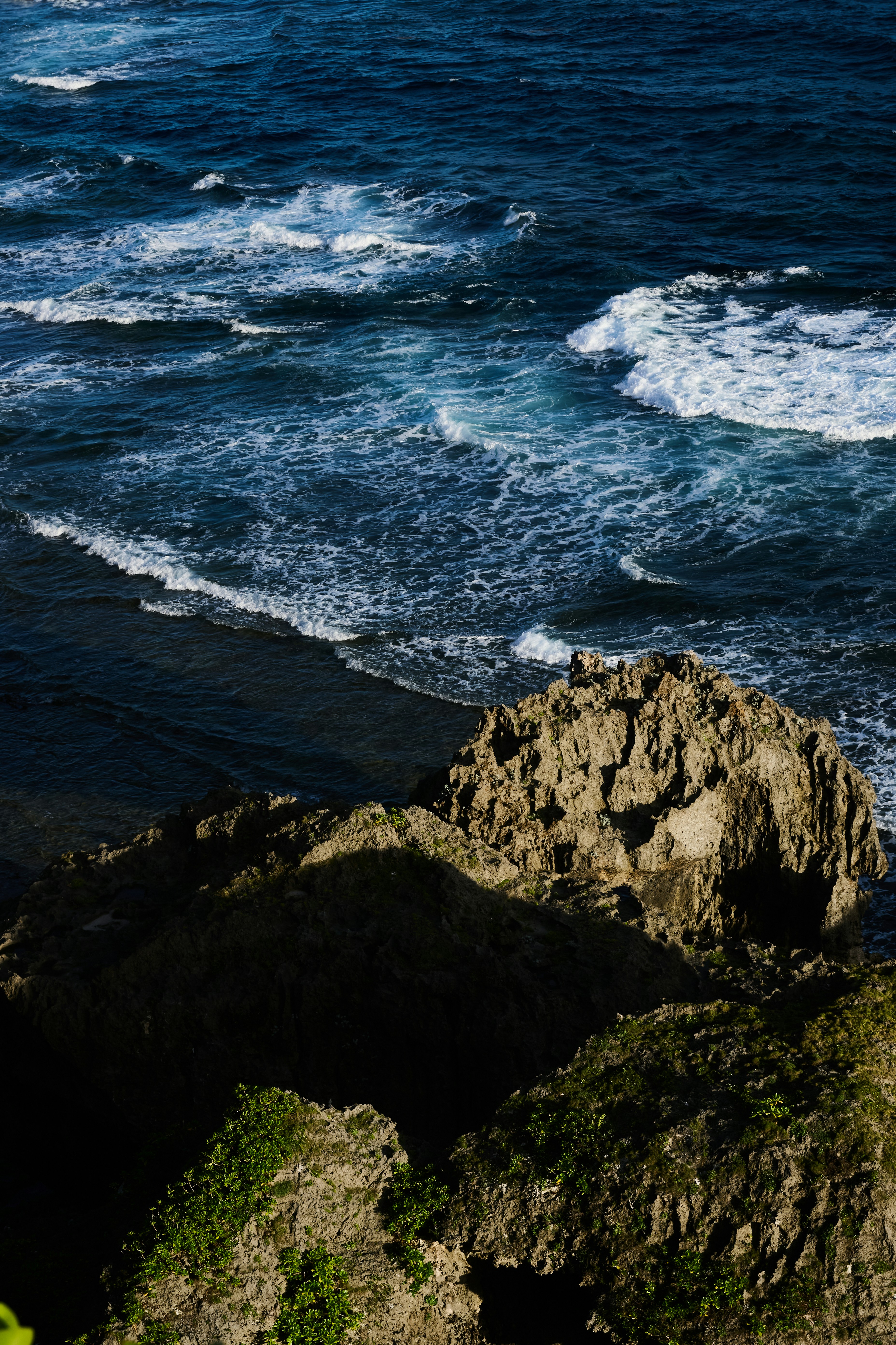 Waves crash against rocky cliffs by the ocean.