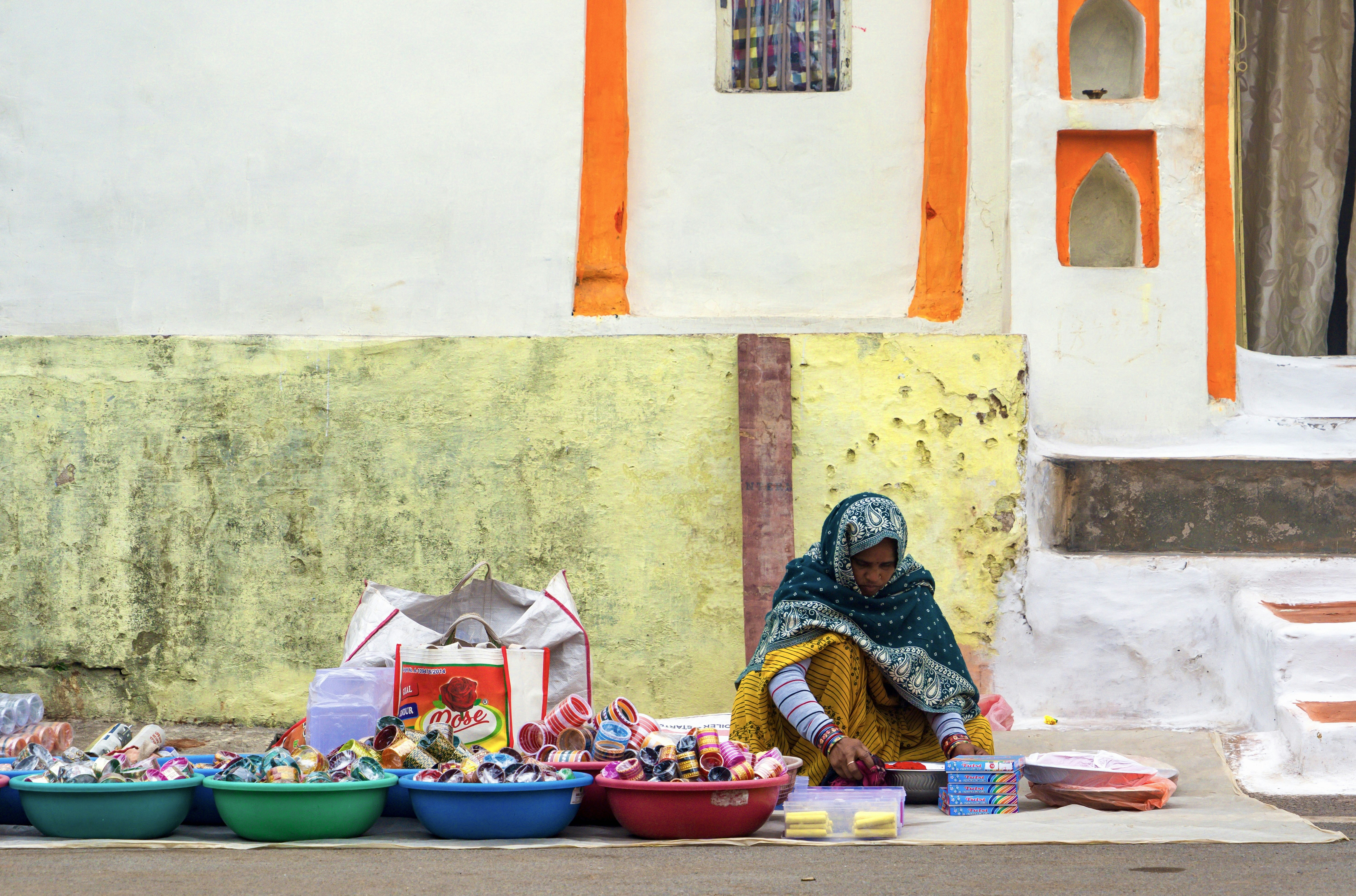 Woman selling colorful sweets from bowls on the street.