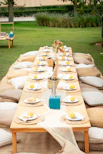 Outdoor picnic table set for a gathering with cushions.