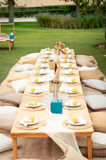 Outdoor picnic table set for a gathering with cushions.