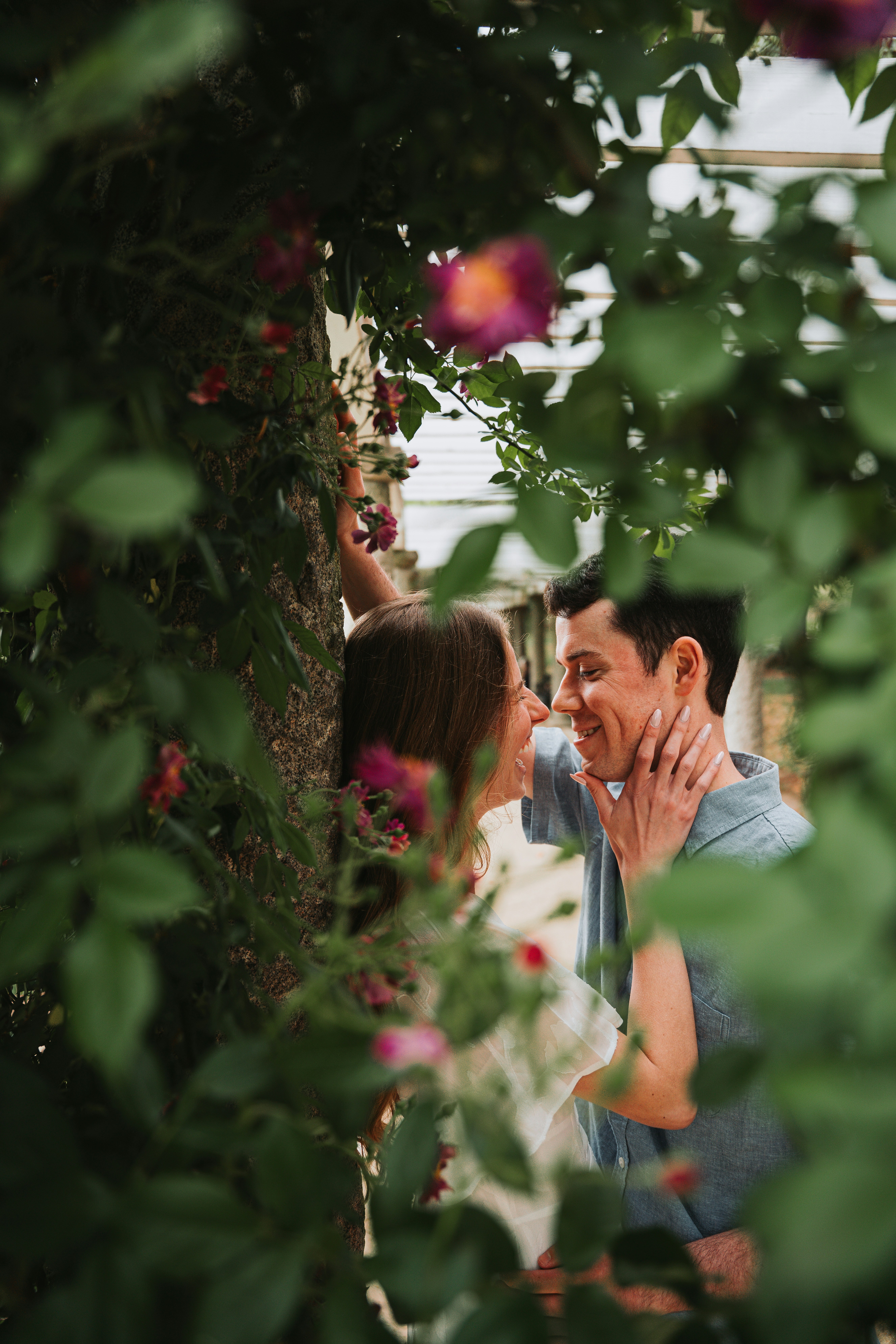 Casal abraçado em meio a flores desabrochando em um jardim