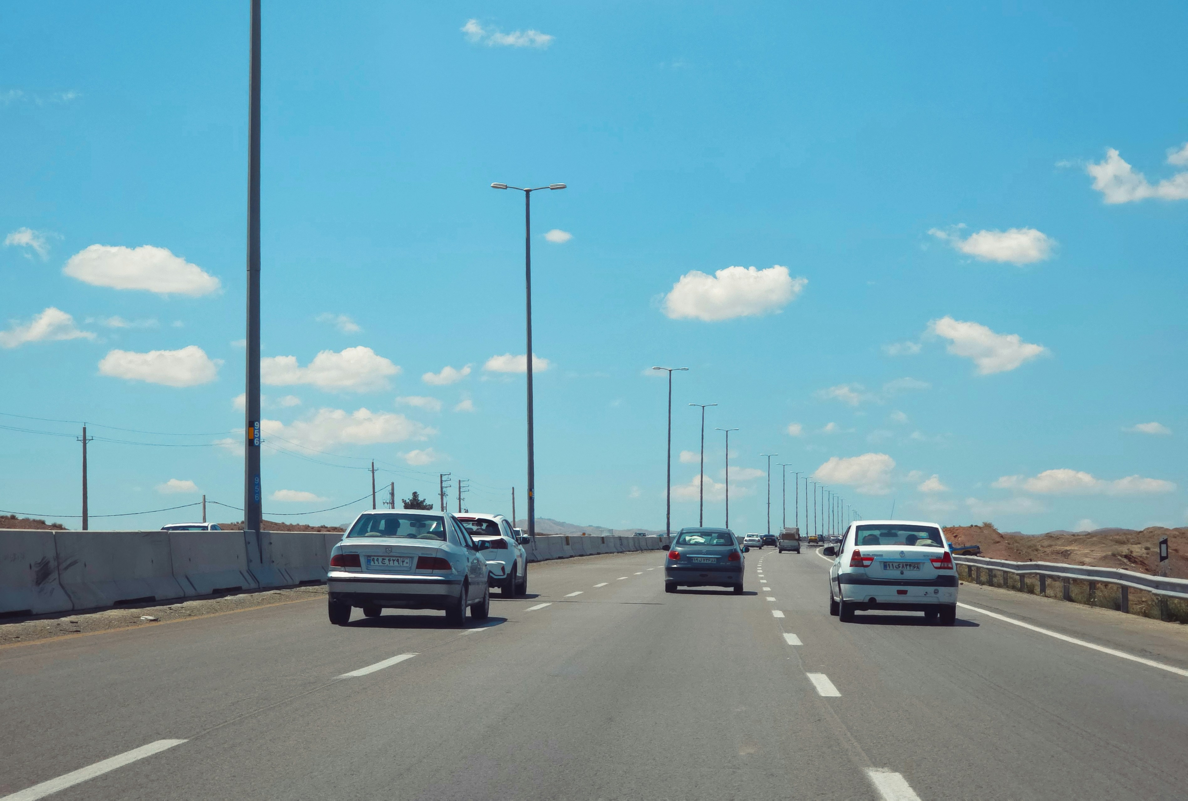 Des voitures roulant sur une autoroute sous un ciel bleu.