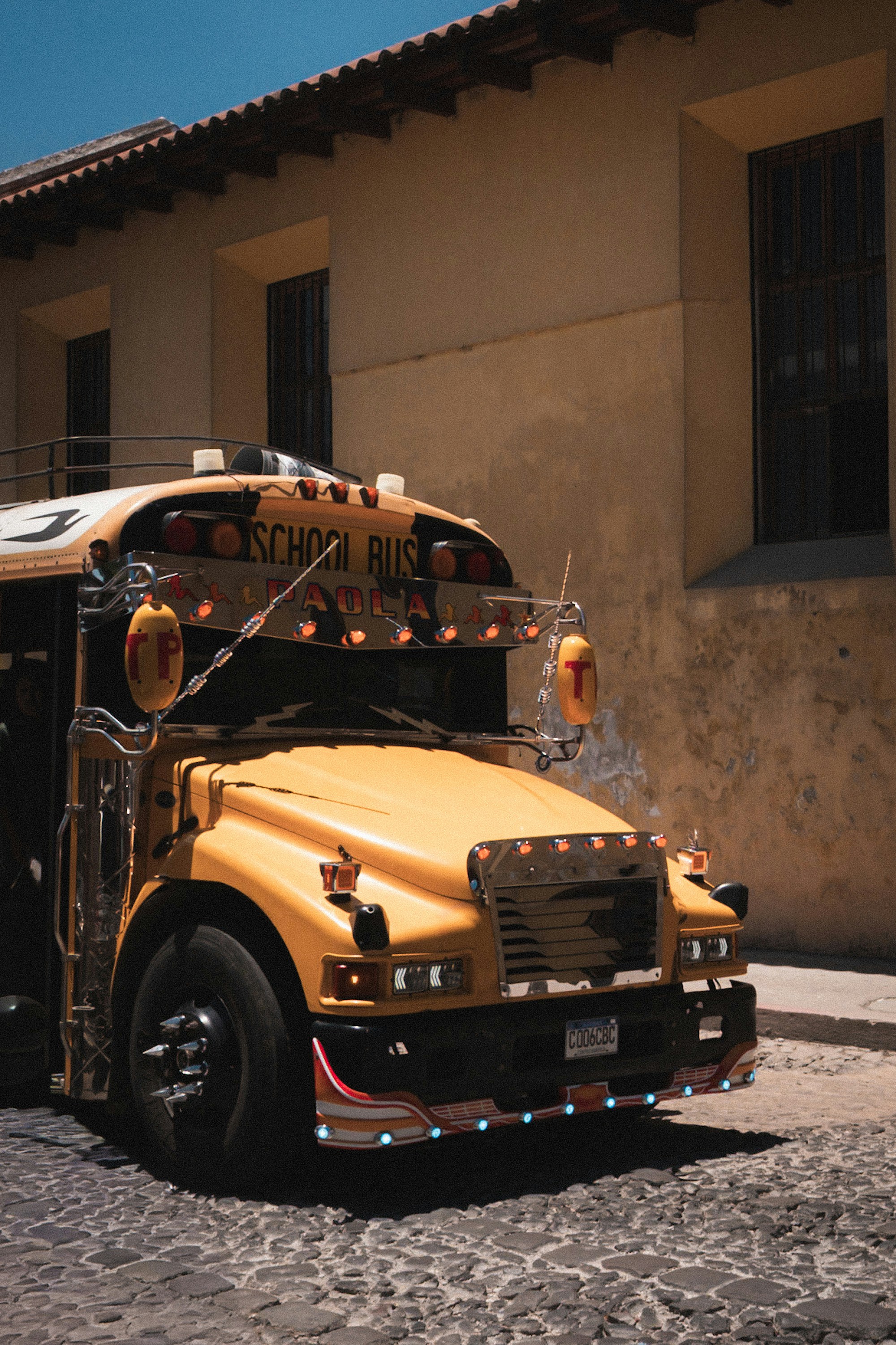 Un bus scolaire jaune garé sur une rue pavée.