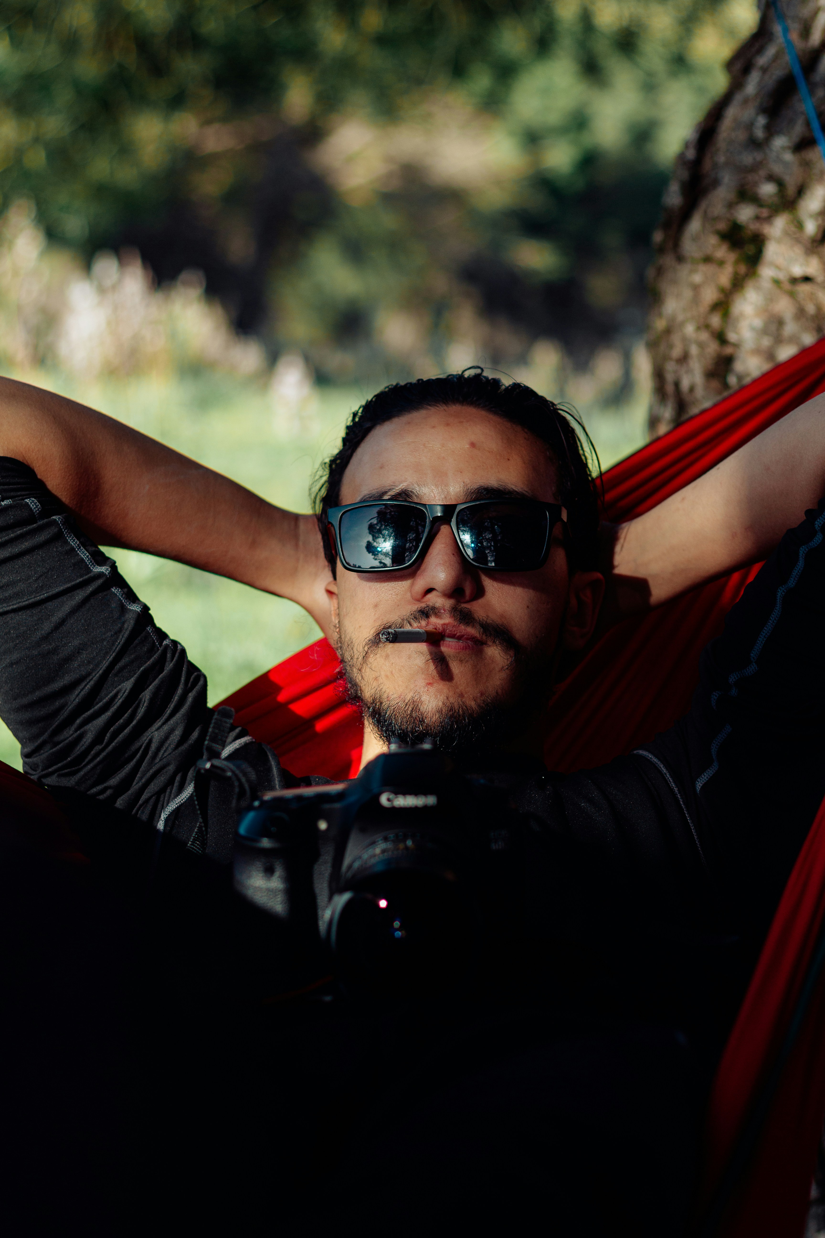 Uomo con gli occhiali da sole che si rilassa in un'amaca rossa.