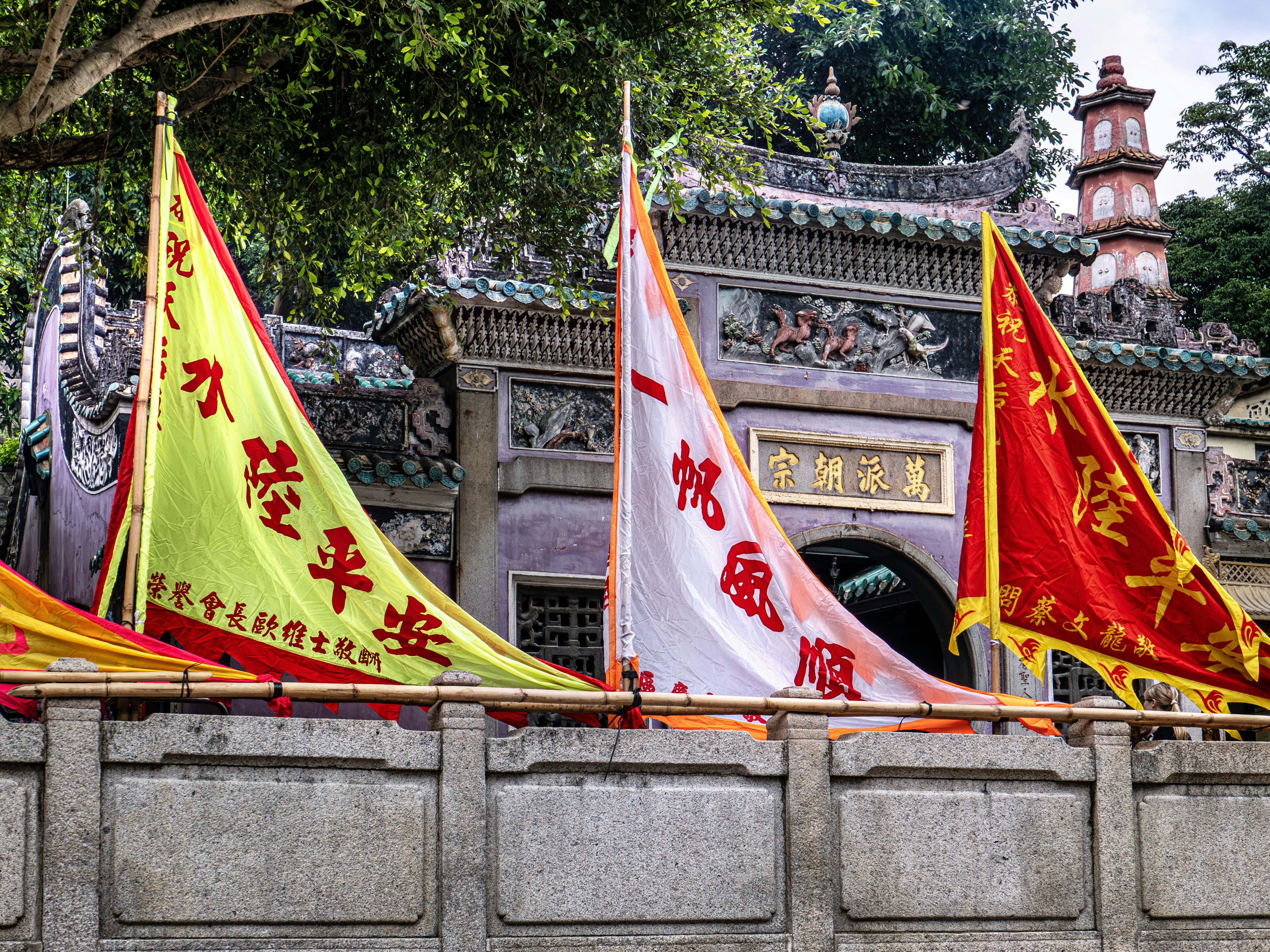 Tres banderas coloridas delante de la entrada de un templo.