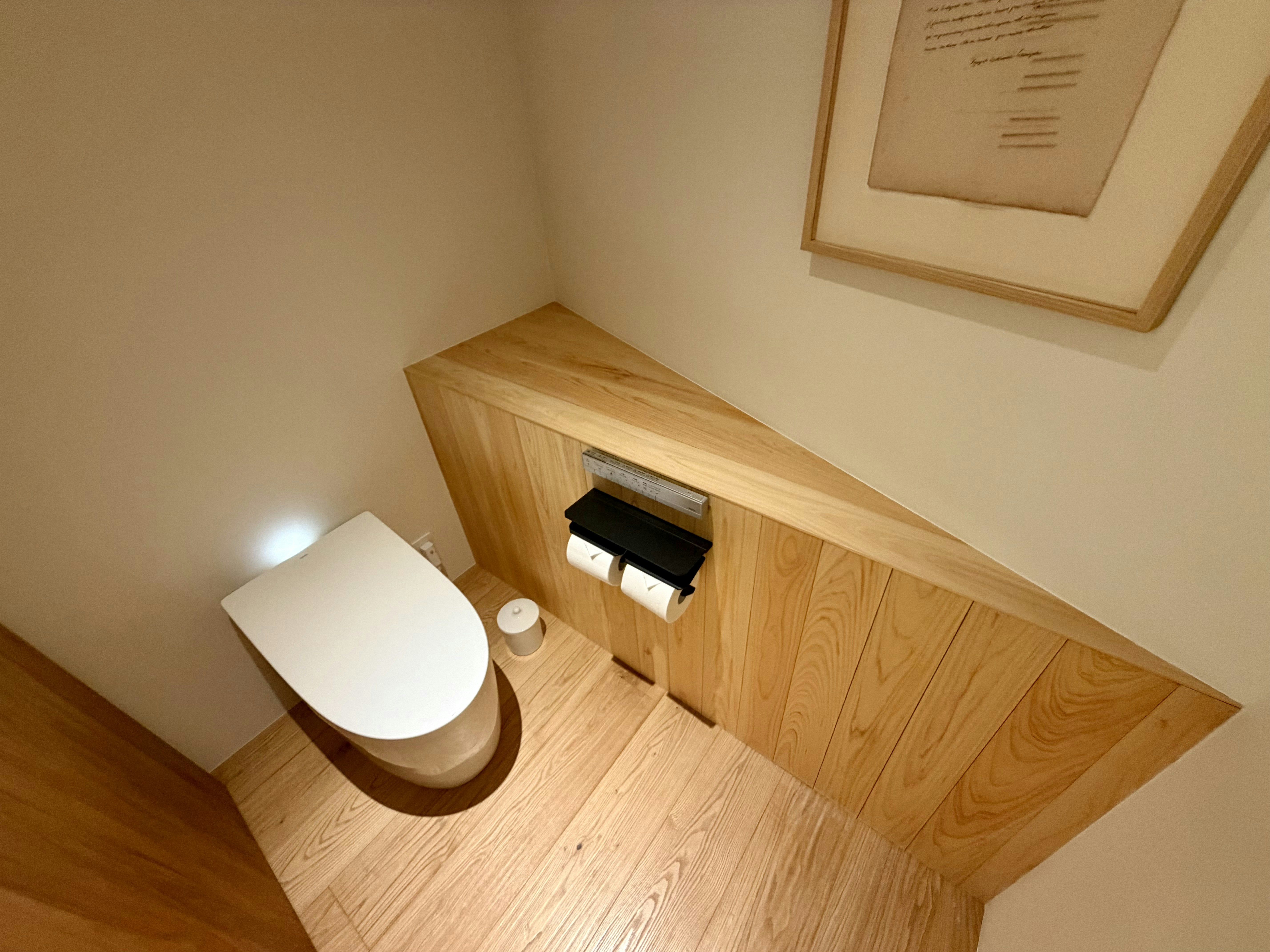 Bagno moderno con dettagli in legno e opere d'arte incorniciate.