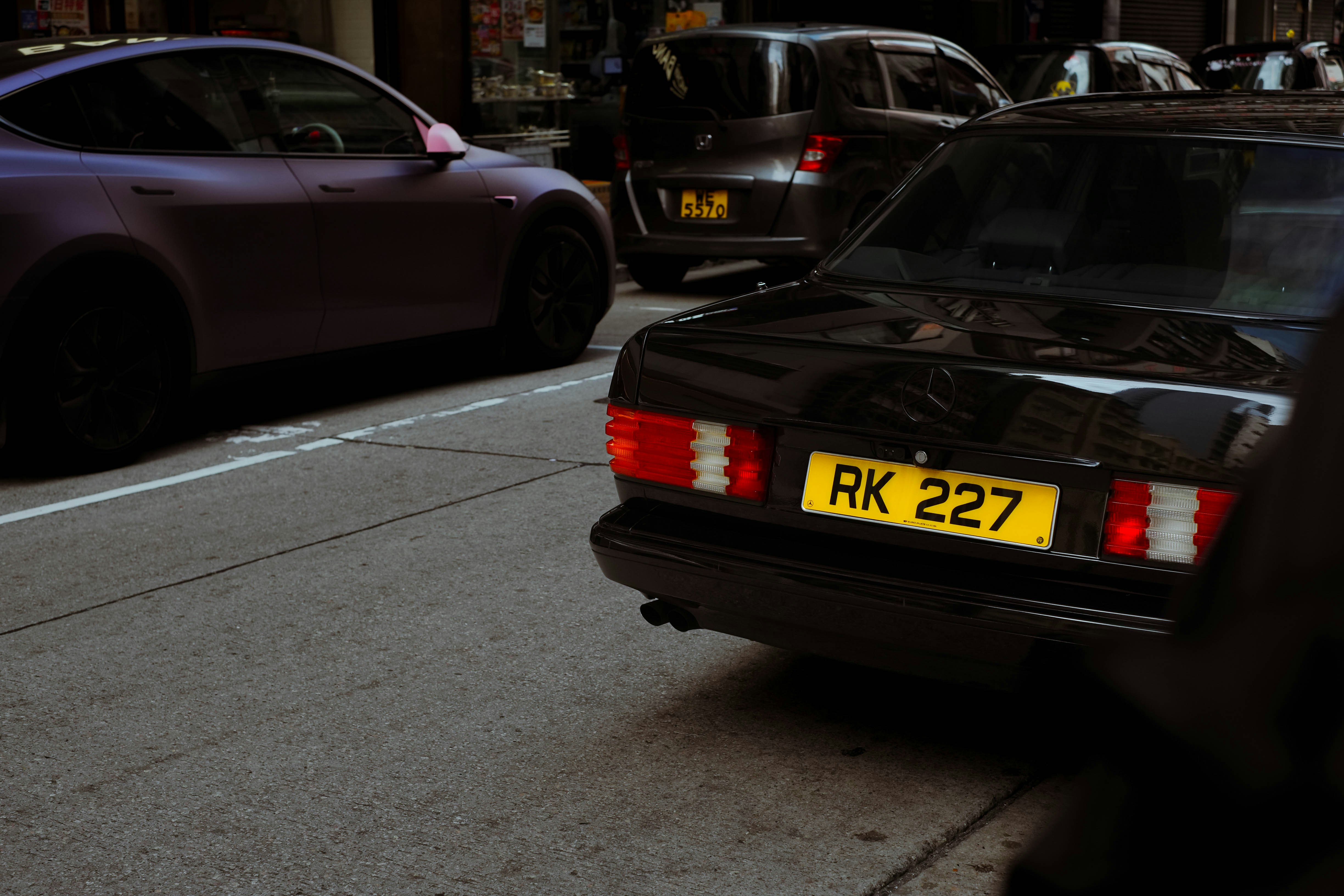 Black car with yellow license plate on street.