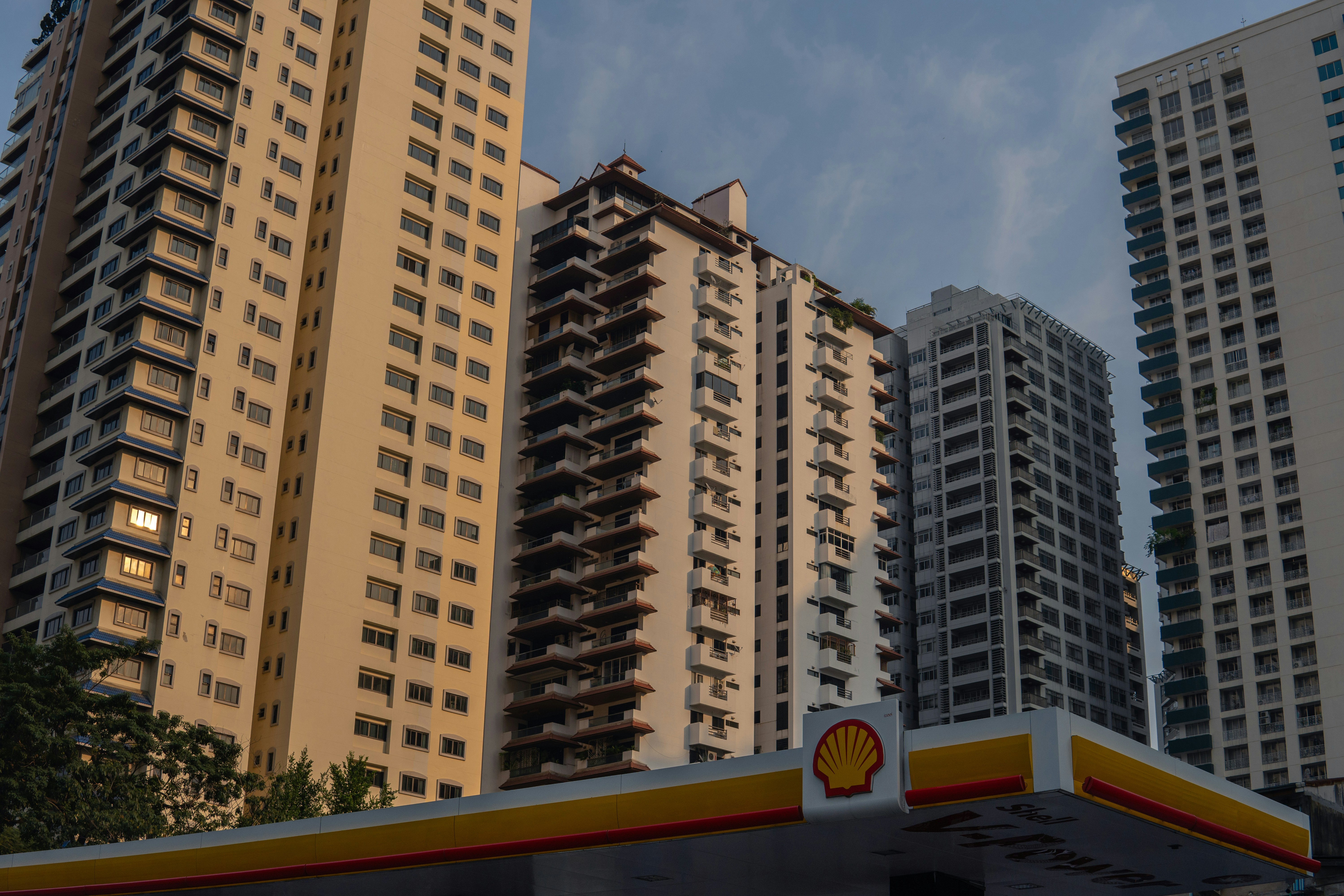 Thai property market housing oversupply - Apartment buildings stand behind a shell gas station.
