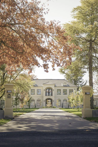 Elegant mansion with autumn trees lining the driveway.