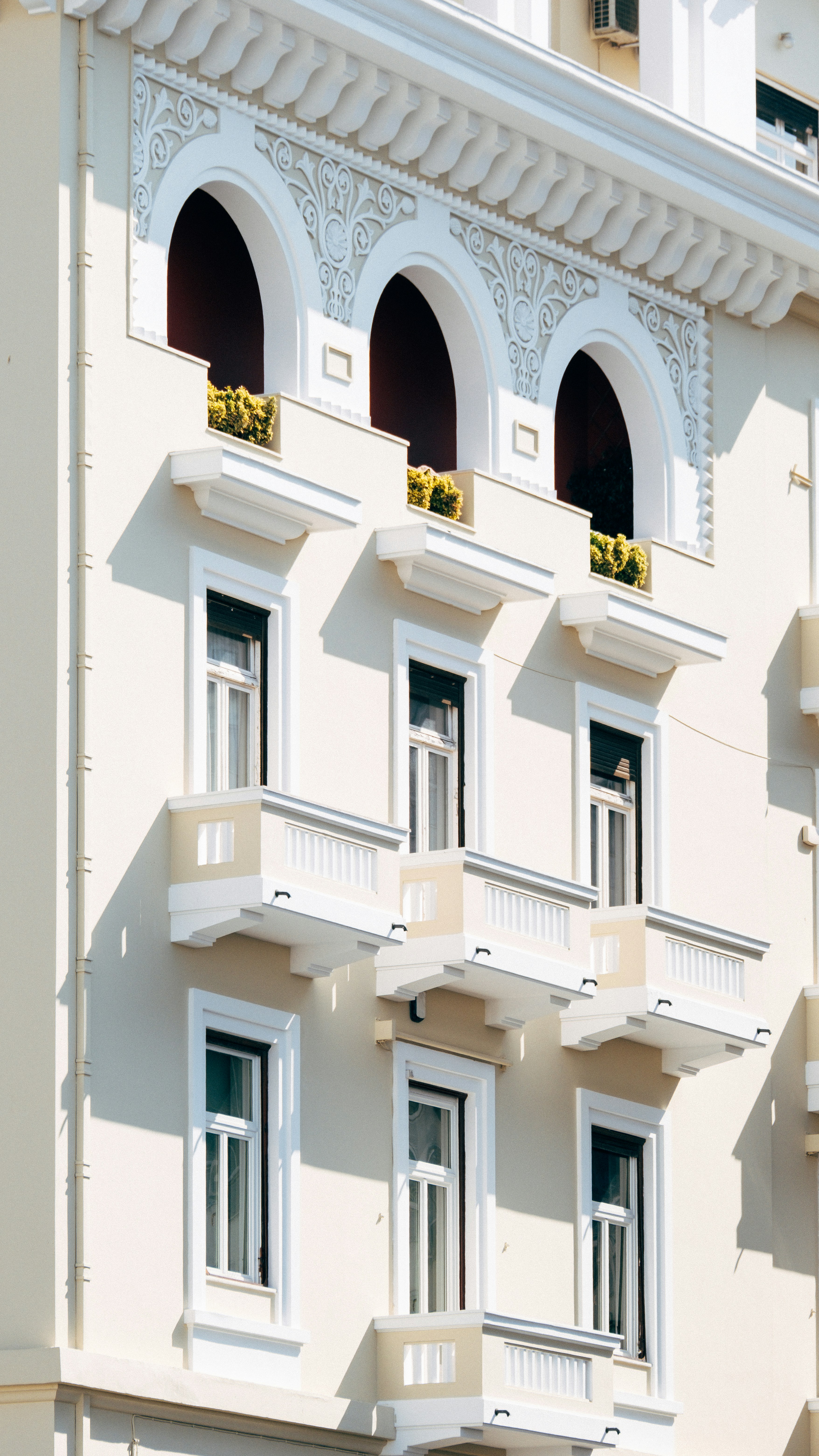 Ornate white building facade with arched windows and balconies.