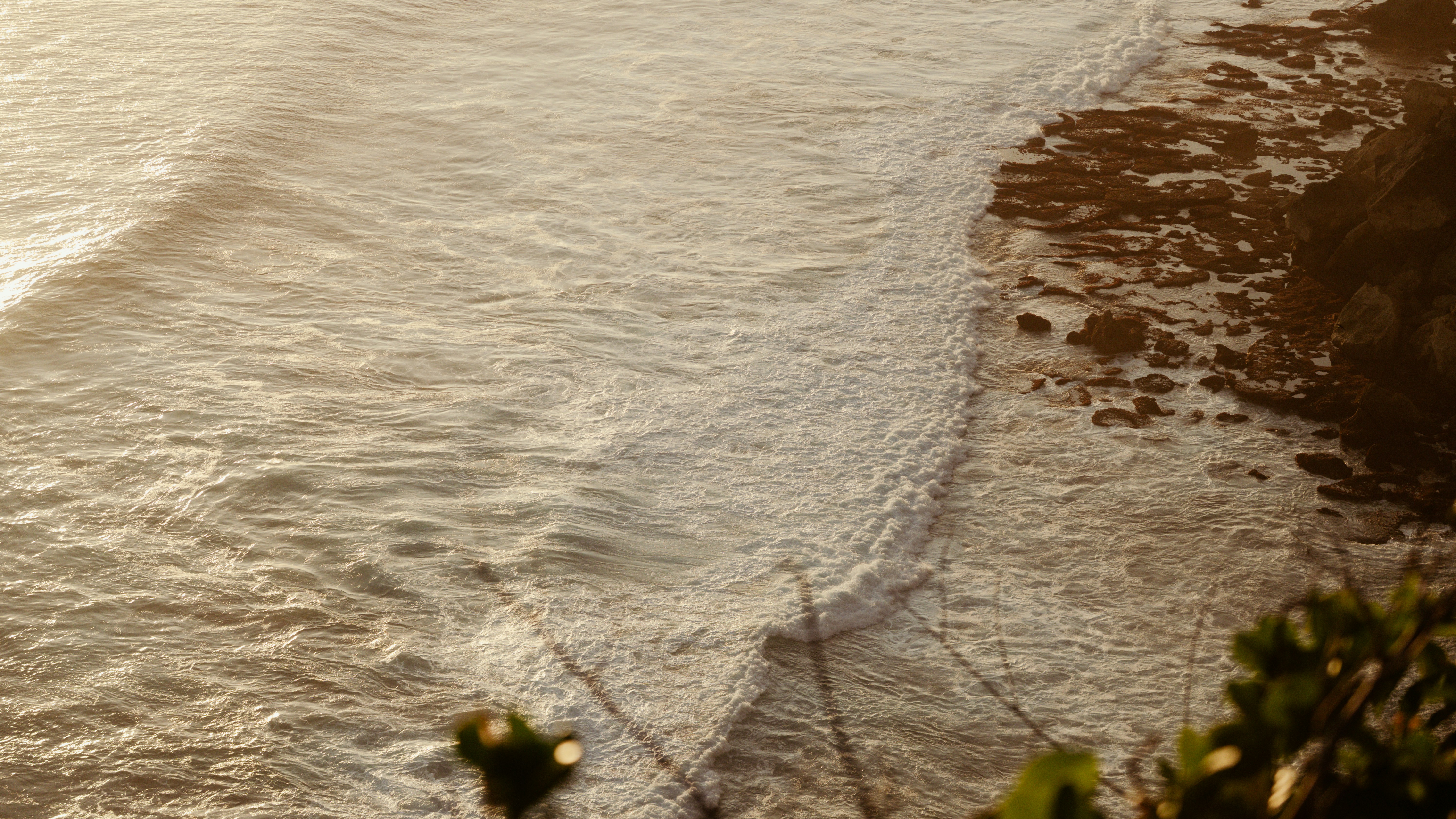 Waves gently crashing on a rocky shore at sunset