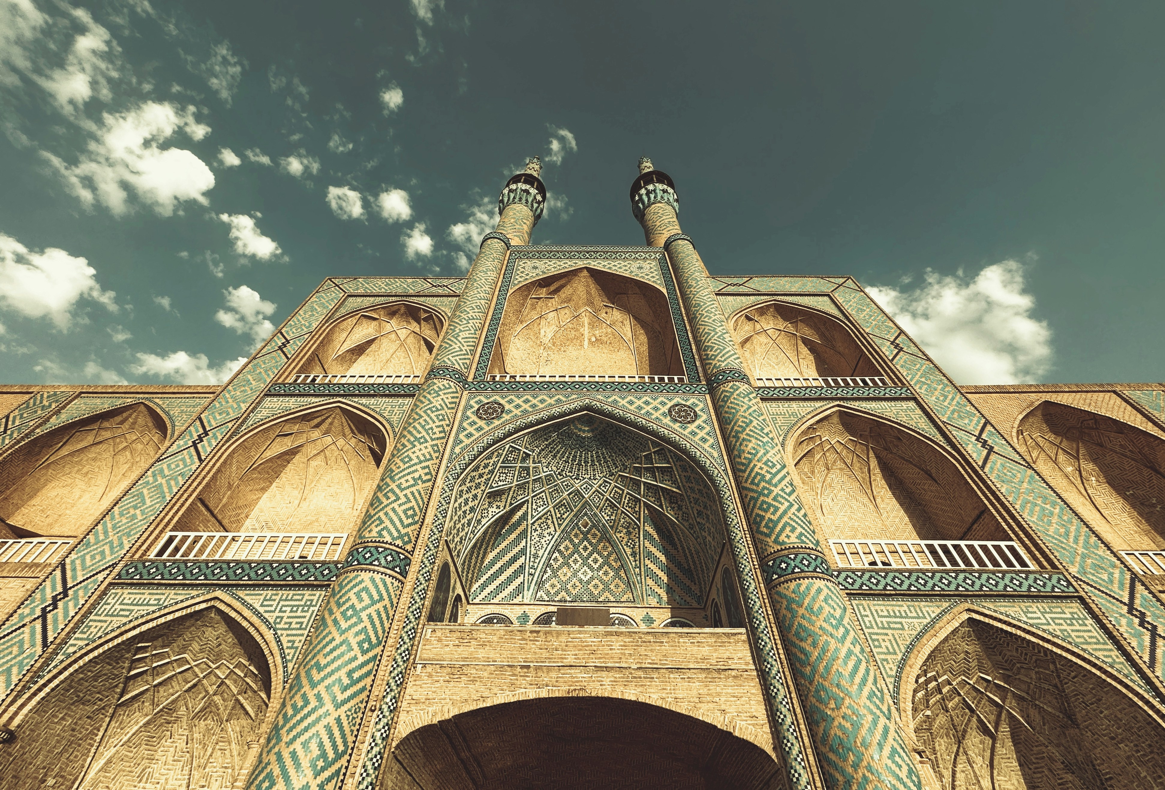Mosquée ornée avec de hauts minarets sur un ciel nuageux.