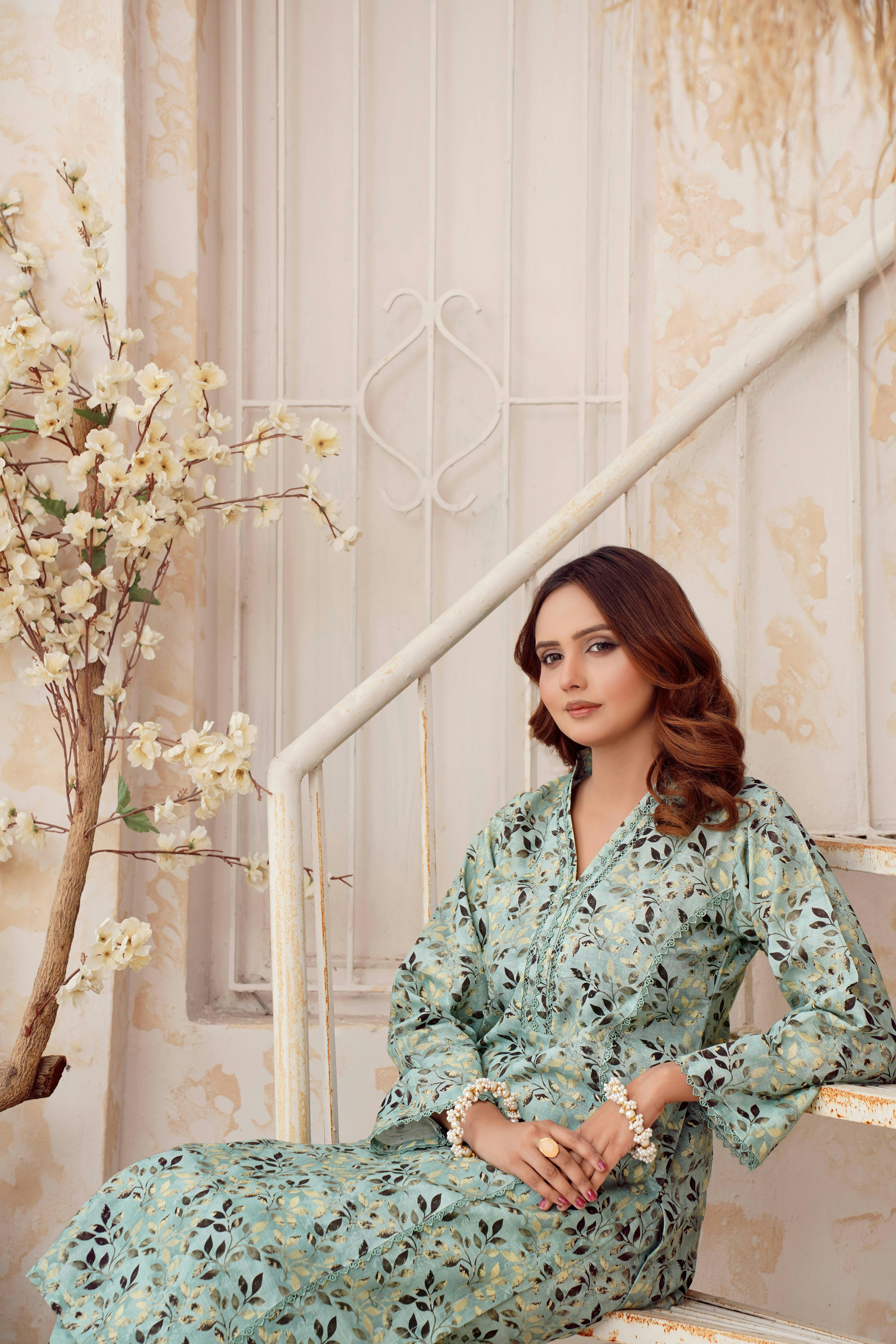 Seorang wanita dengan gaun bermotif duduk di tangga.