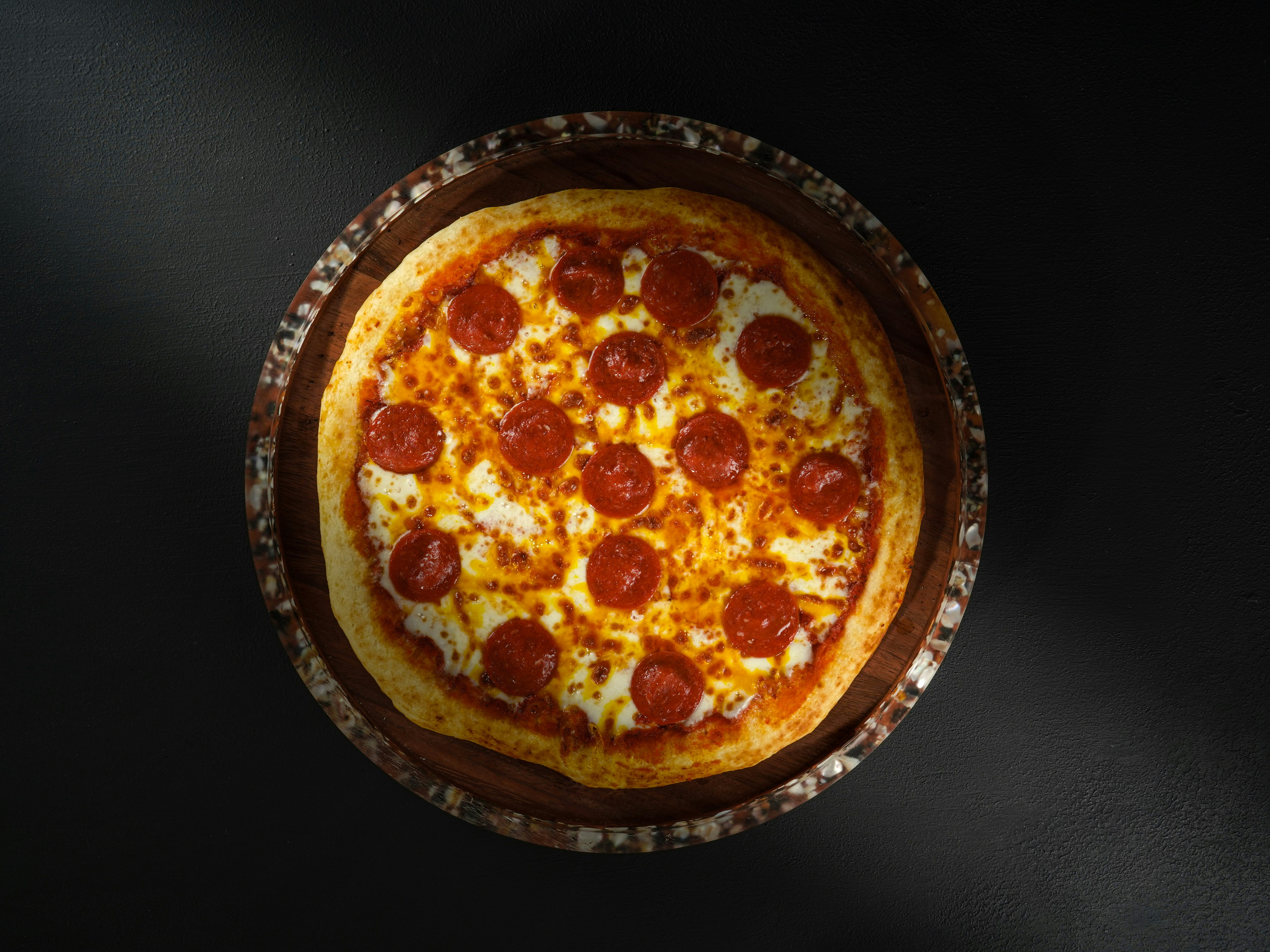 Whole pepperoni pizza on a dark background
