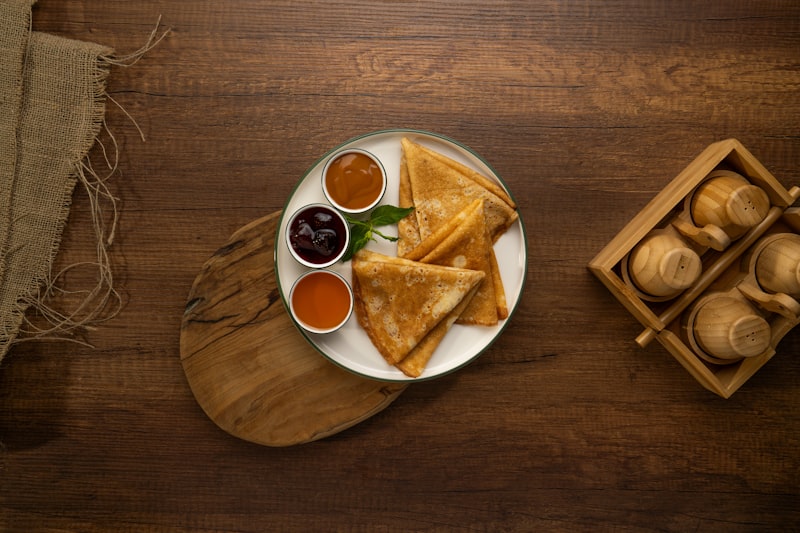 Thin crepes served with jars of jam on a wooden table
