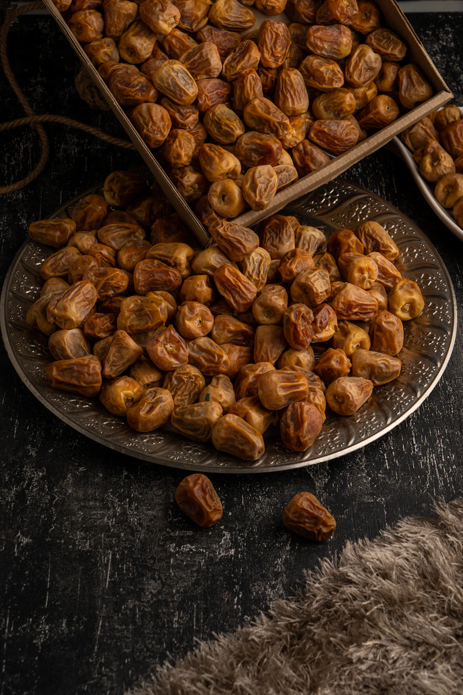 Golden dates spilling from a wooden tray onto an engraved metal plate