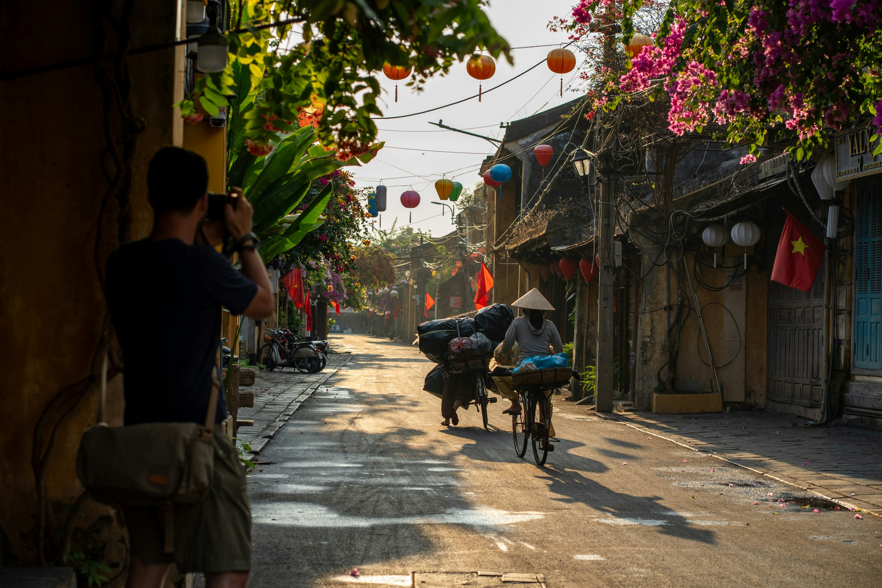 A photographer captures a street scene with cyclists and lanterns.