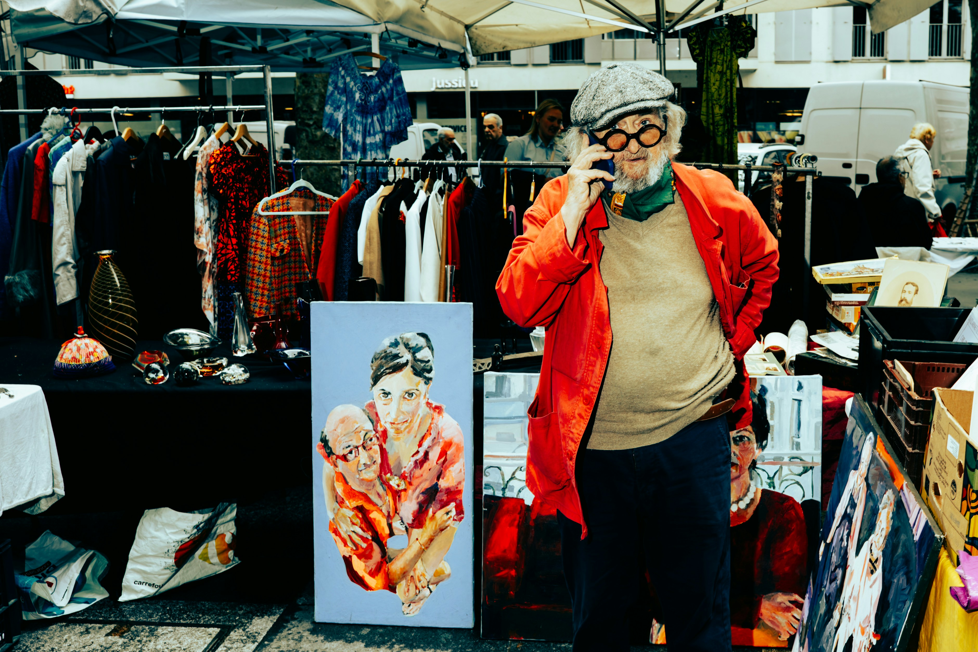 Uomo con cappello e occhiali parla al telefono al mercato.