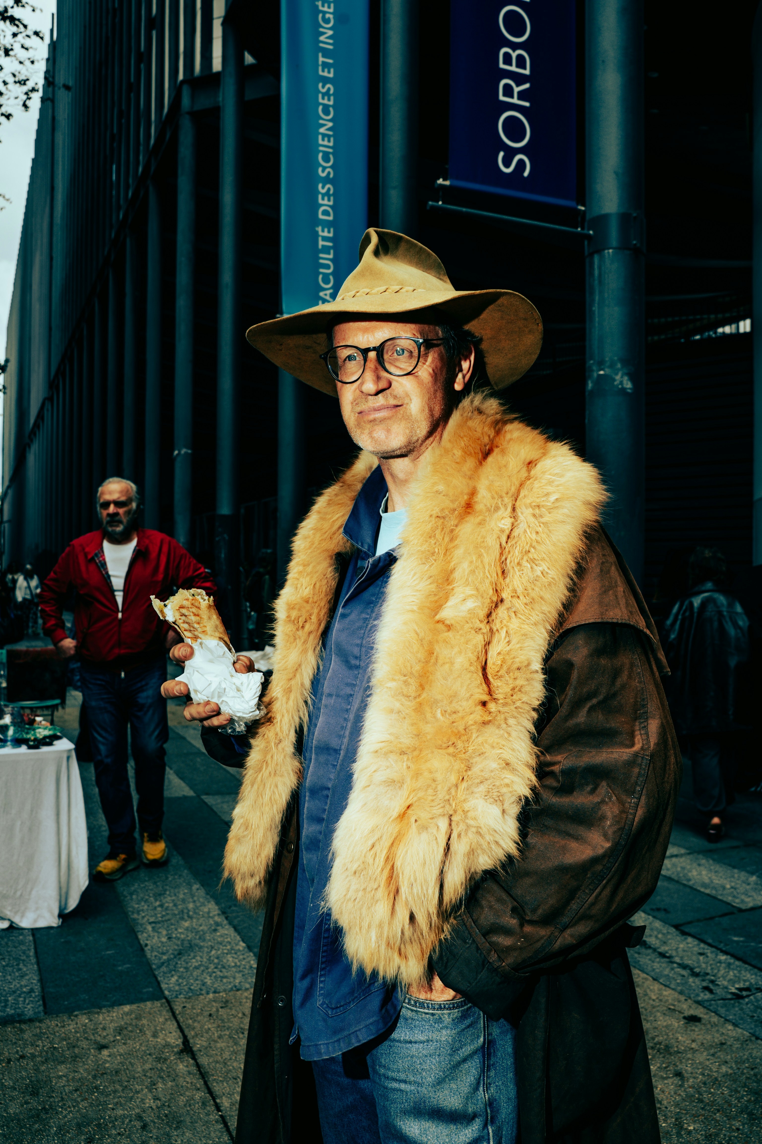 Un uomo con cappello e cappotto di pelliccia tiene il cibo fuori.