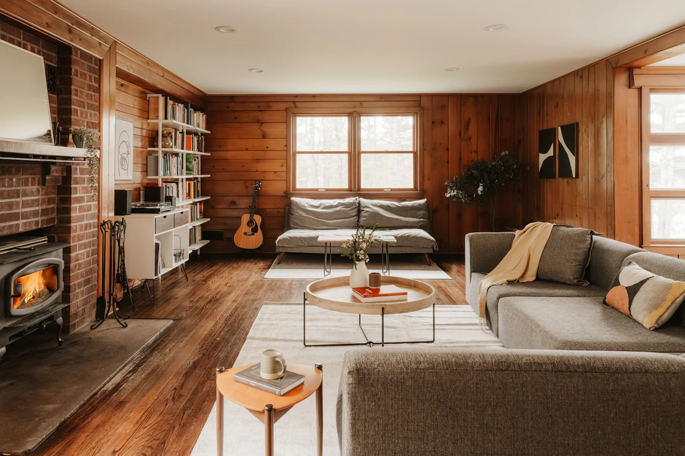 Warm log home living room with wood stove, bookshelves and leather seating