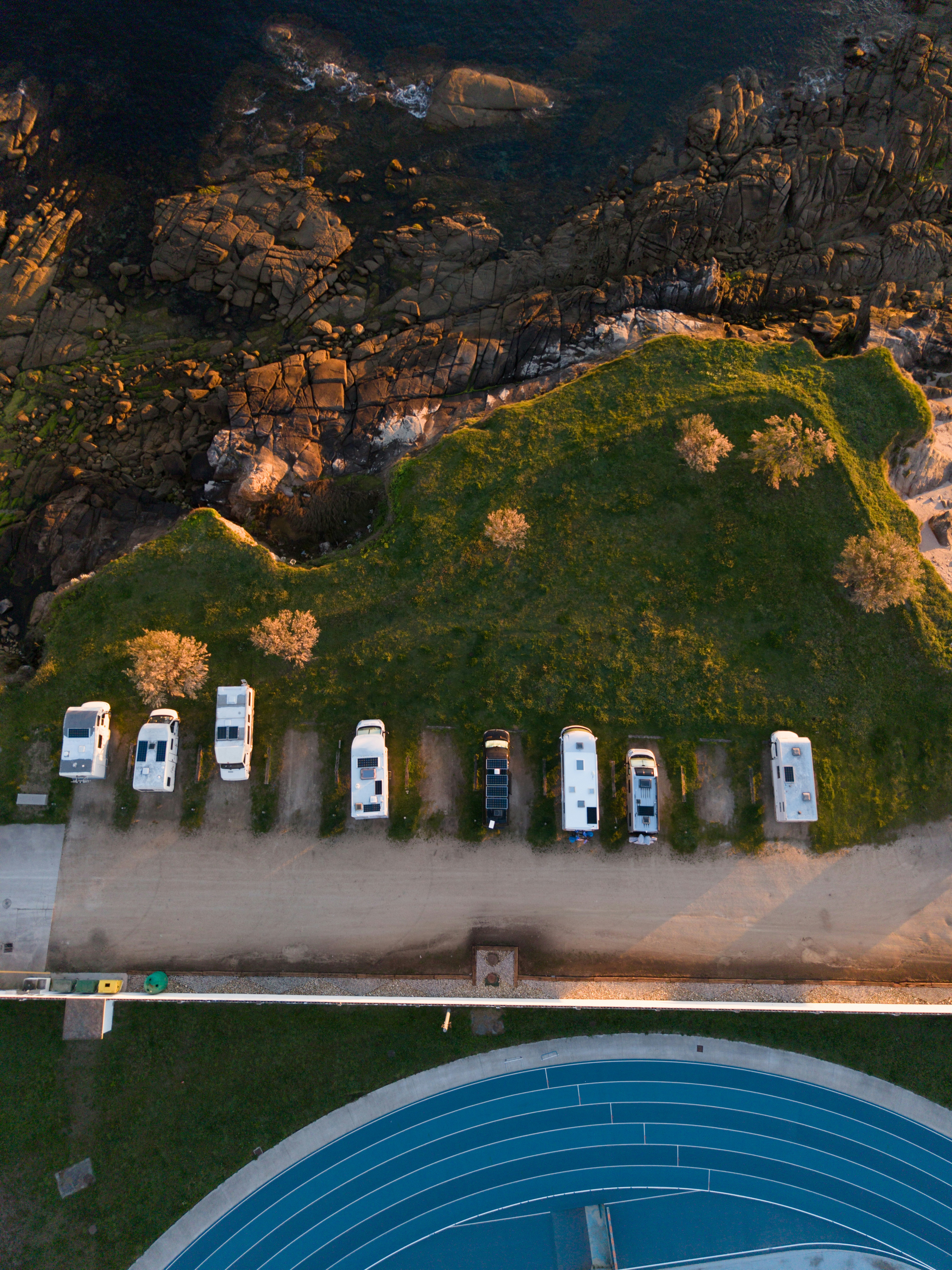 Autocaravanas aparcadas a lo largo de una costa cubierta de hierba cerca de una pista azul.